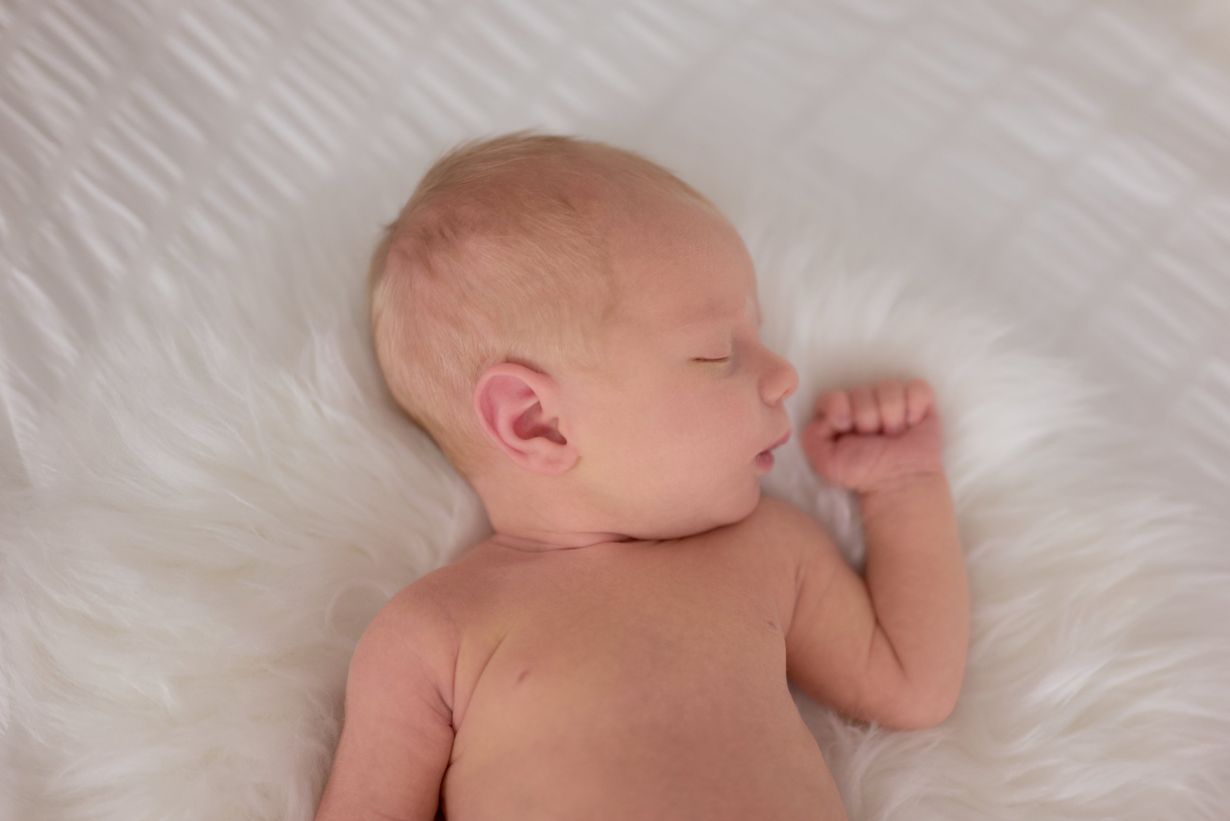 Newborn baby sleeping on a soft white surface