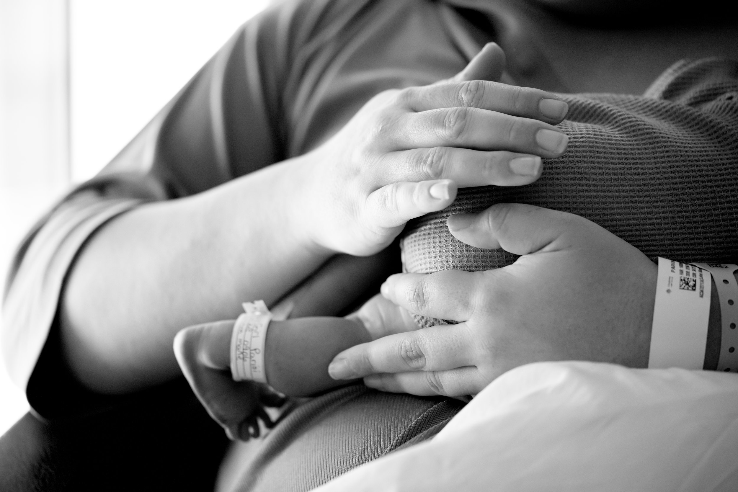 A person's hand resting on another person's chest with an IV line attached, suggesting a hospital or medical setting.