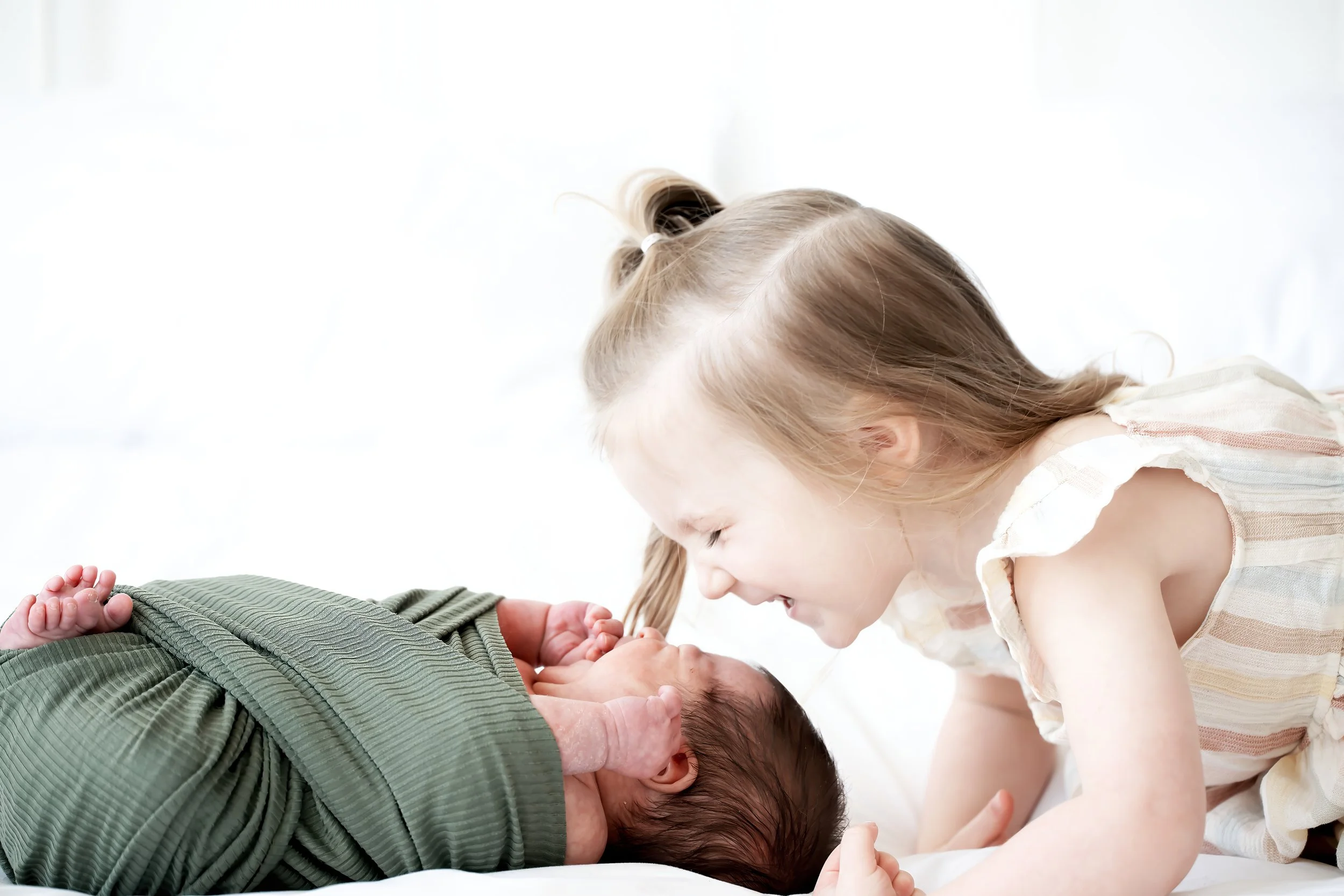 A young girl with light brown hair, tied in a ponytail, kisses a man who is lying down and has his head turned to the side. The girl appears to be happy and tender, showing affection to the man.