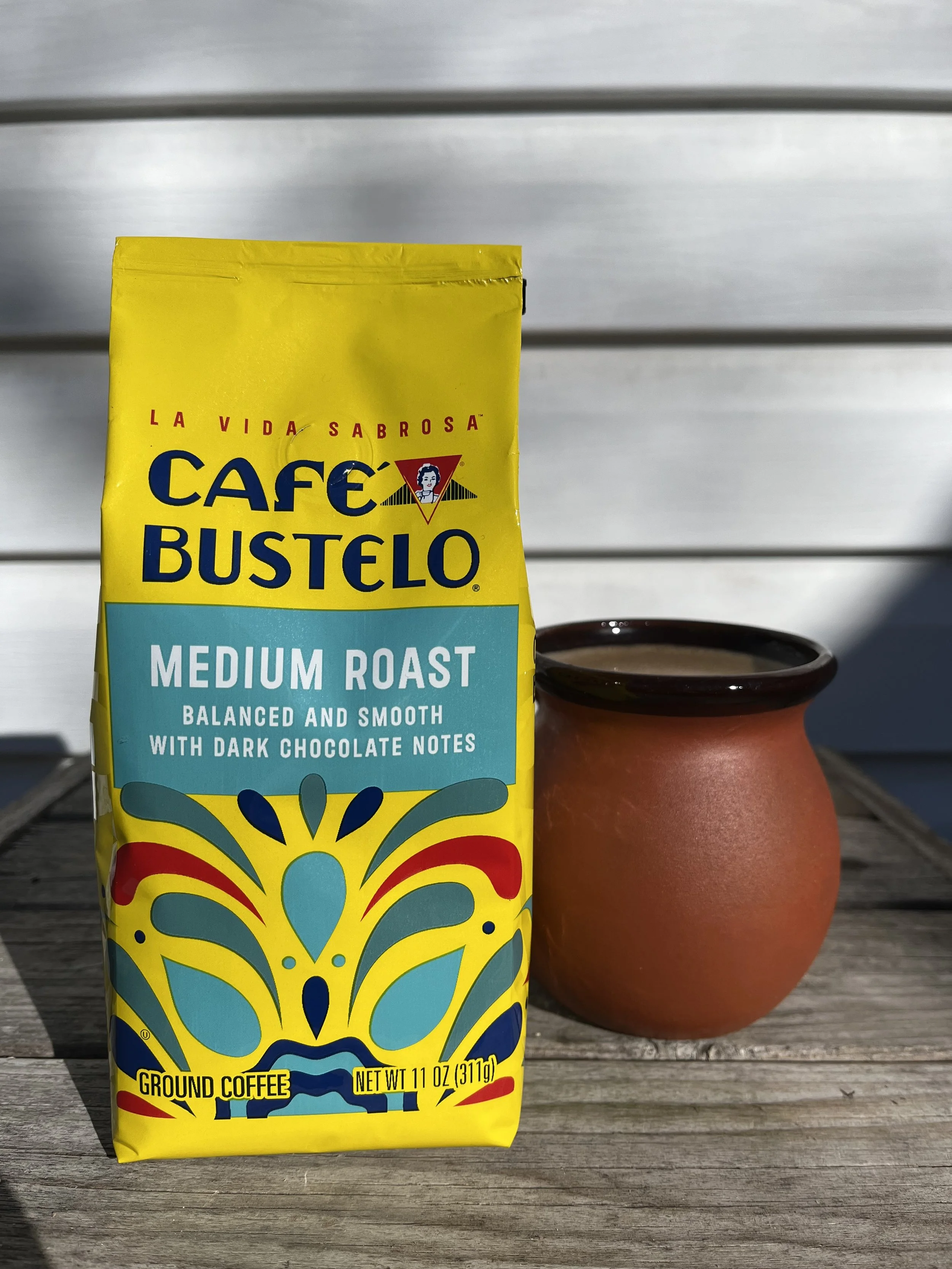 bag of coffee grounds next to a clay mug