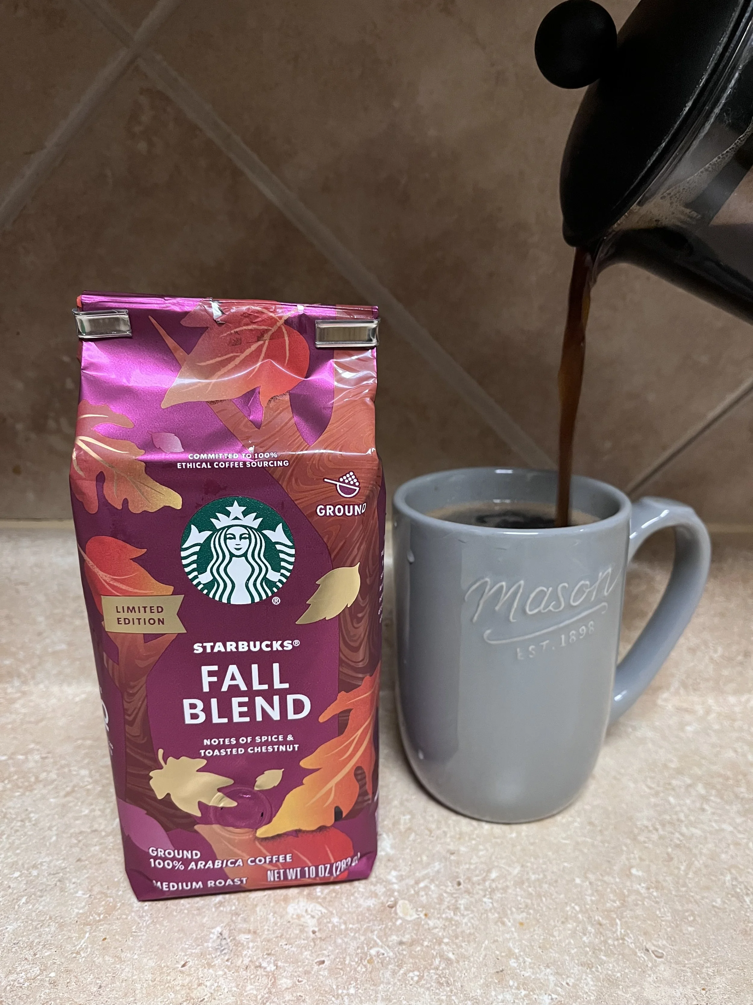 french press pouring into a mug, next to a bag of Starbucks coffee