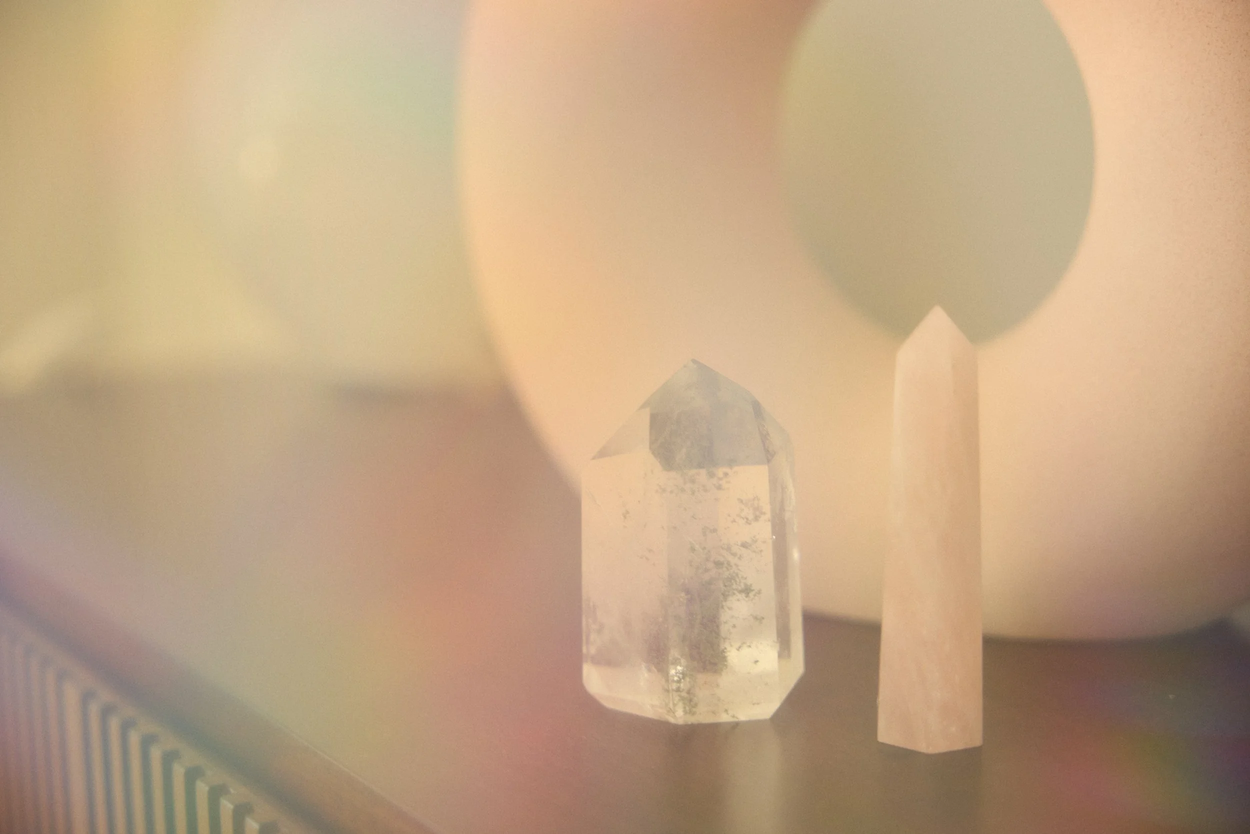 Close-up of a clear, faceted crystal with a house reflection inside, placed on a beige surface with a striped pattern in the background.