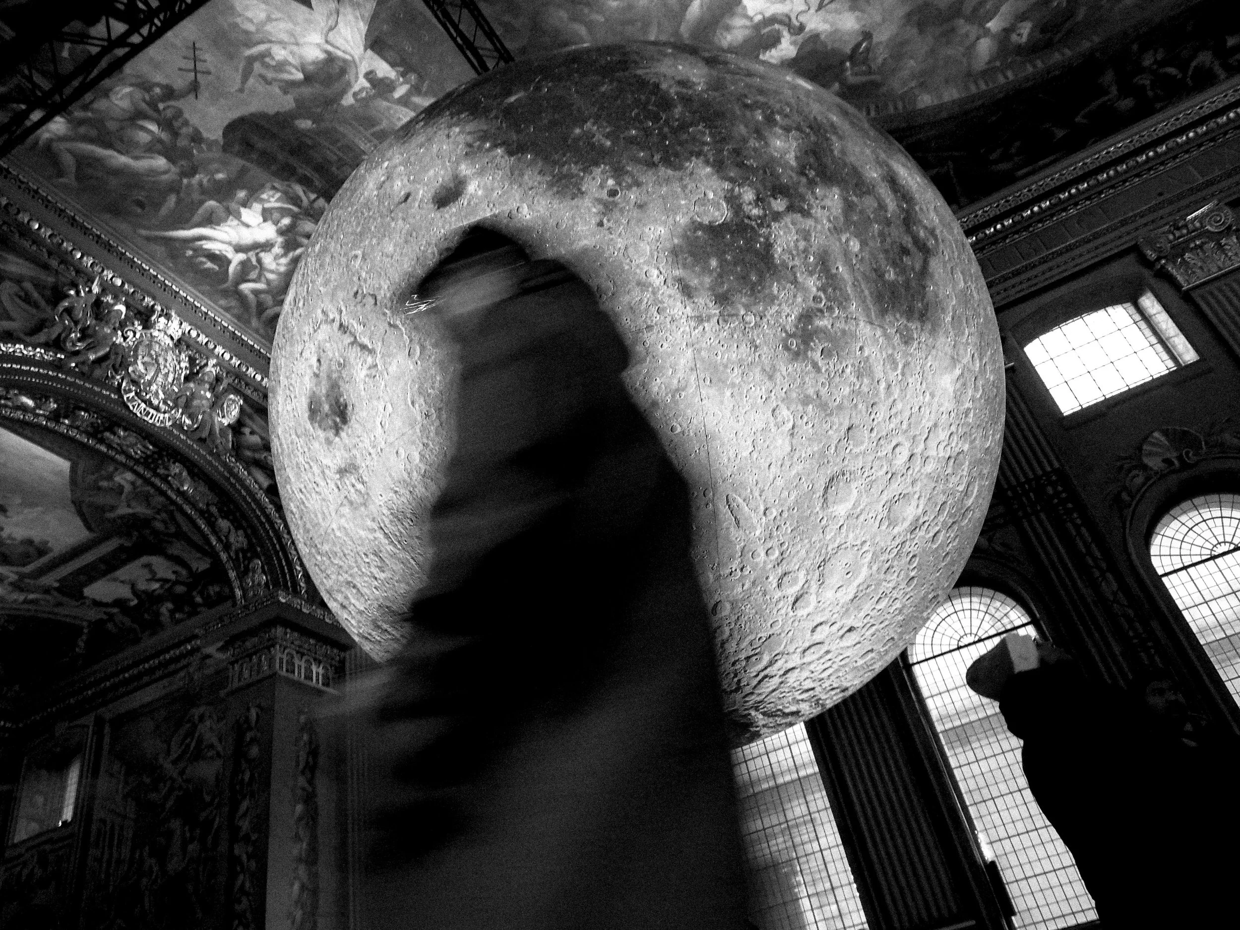 A large, detailed model of the moon displayed indoors, with ornate architectural details and murals on the walls behind it.