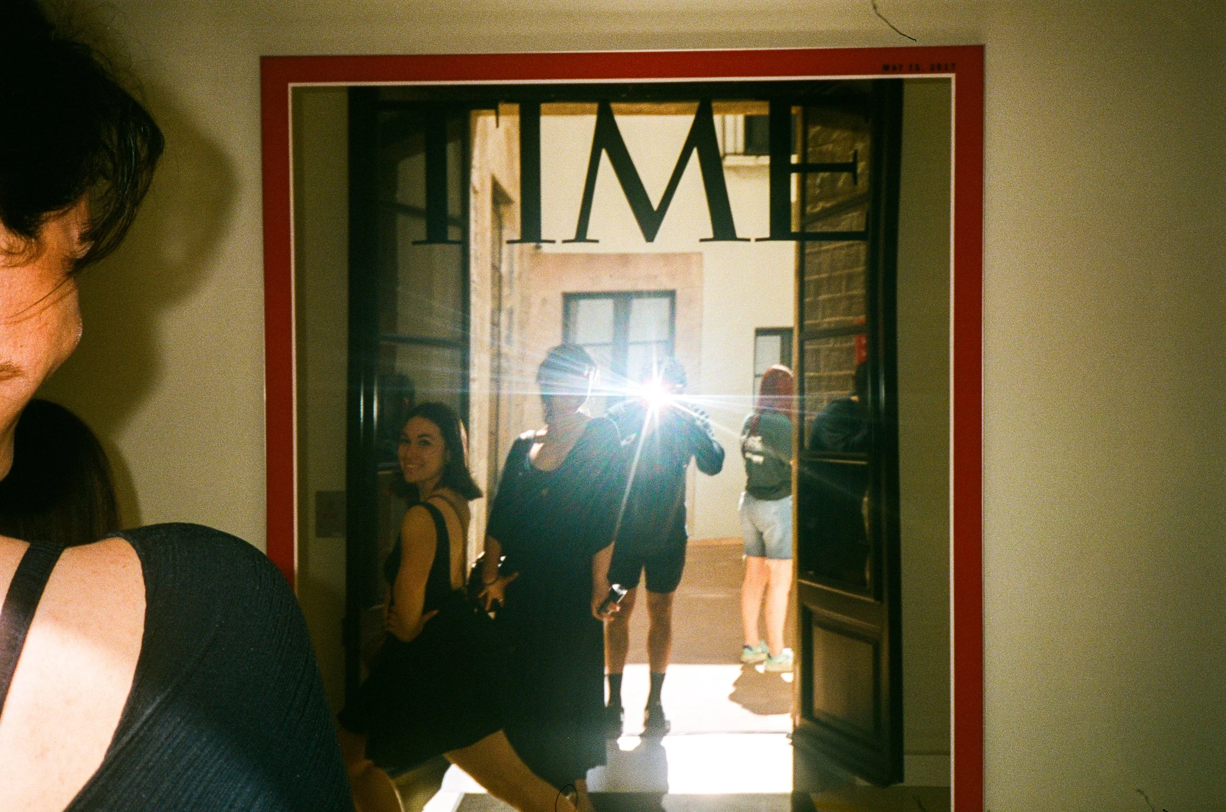 Reflection of people walking through a doorway in a mirror with a red border.