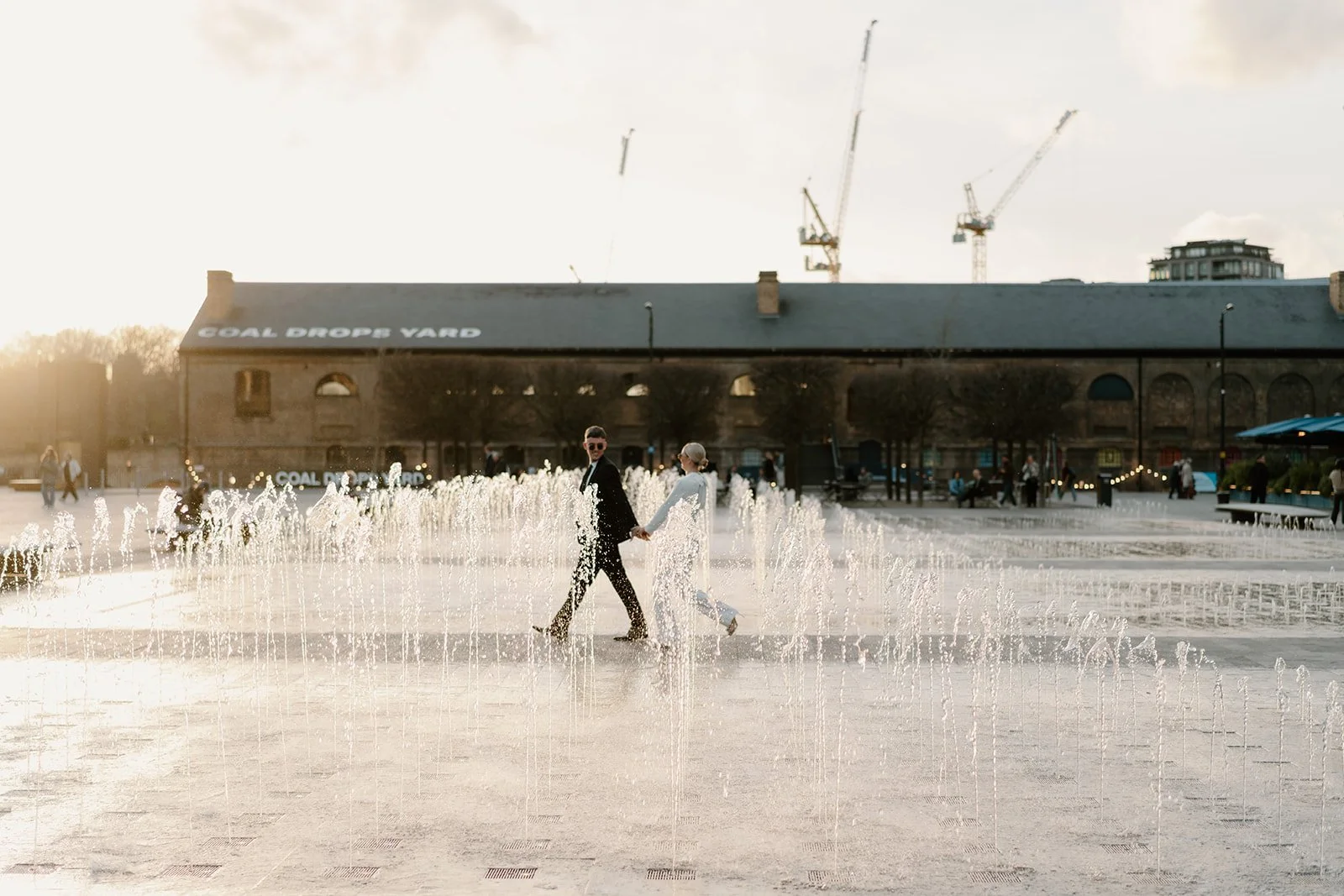 Couple walking through the fountains at Coal Drops Yard during their London town hall wedding portraits