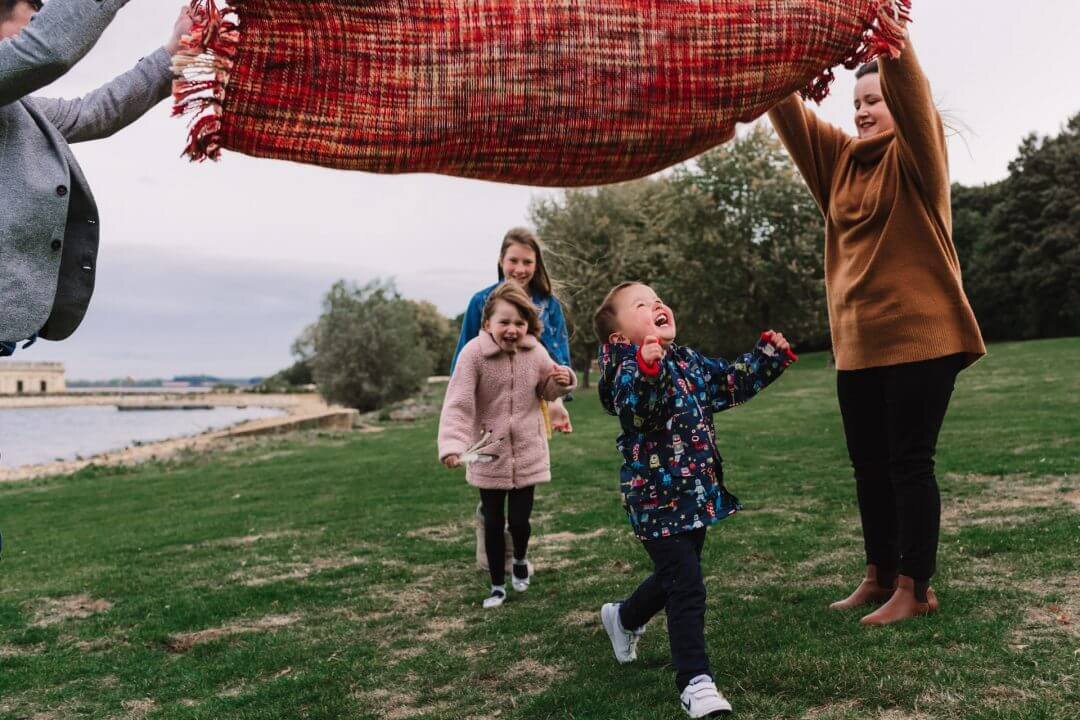family playing parachute with picnic blanket Rutland Water family photography