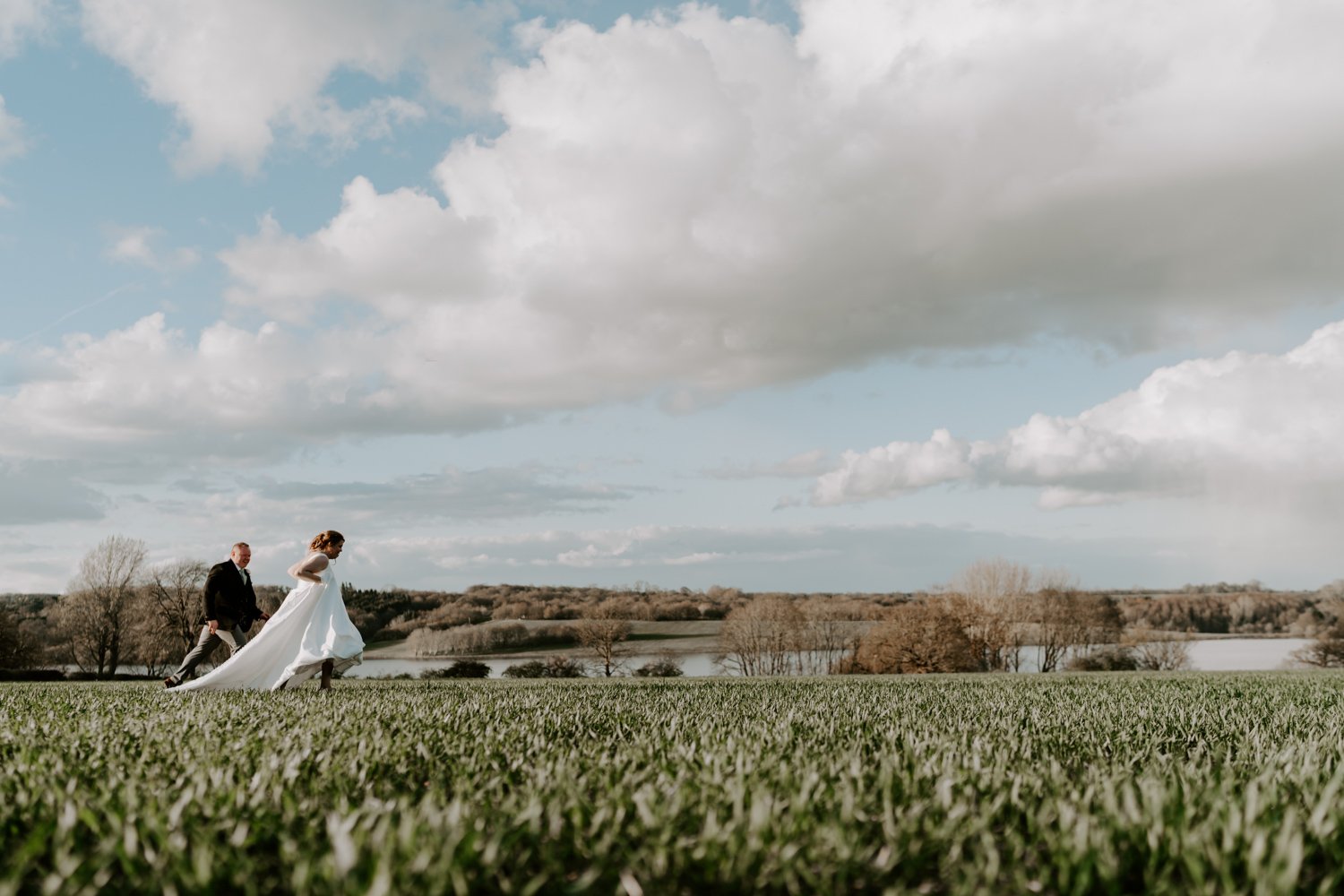 couple running against backdrop of Hambleton peninsula Halfmoon farm wedding Rutland 