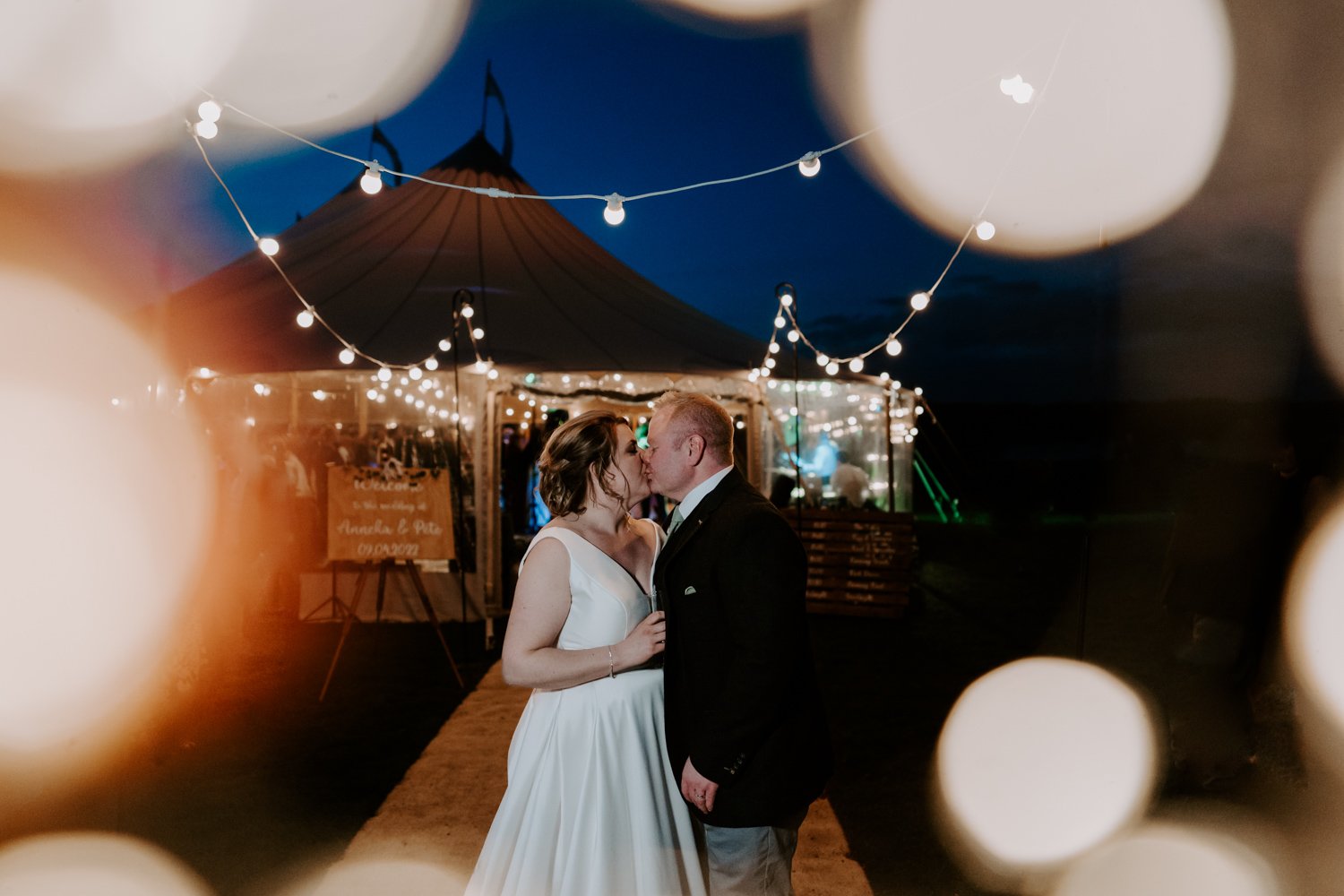 bride groom kissing entrance to marquee nightime fairy lights Halfmoon farm wedding Hambleton