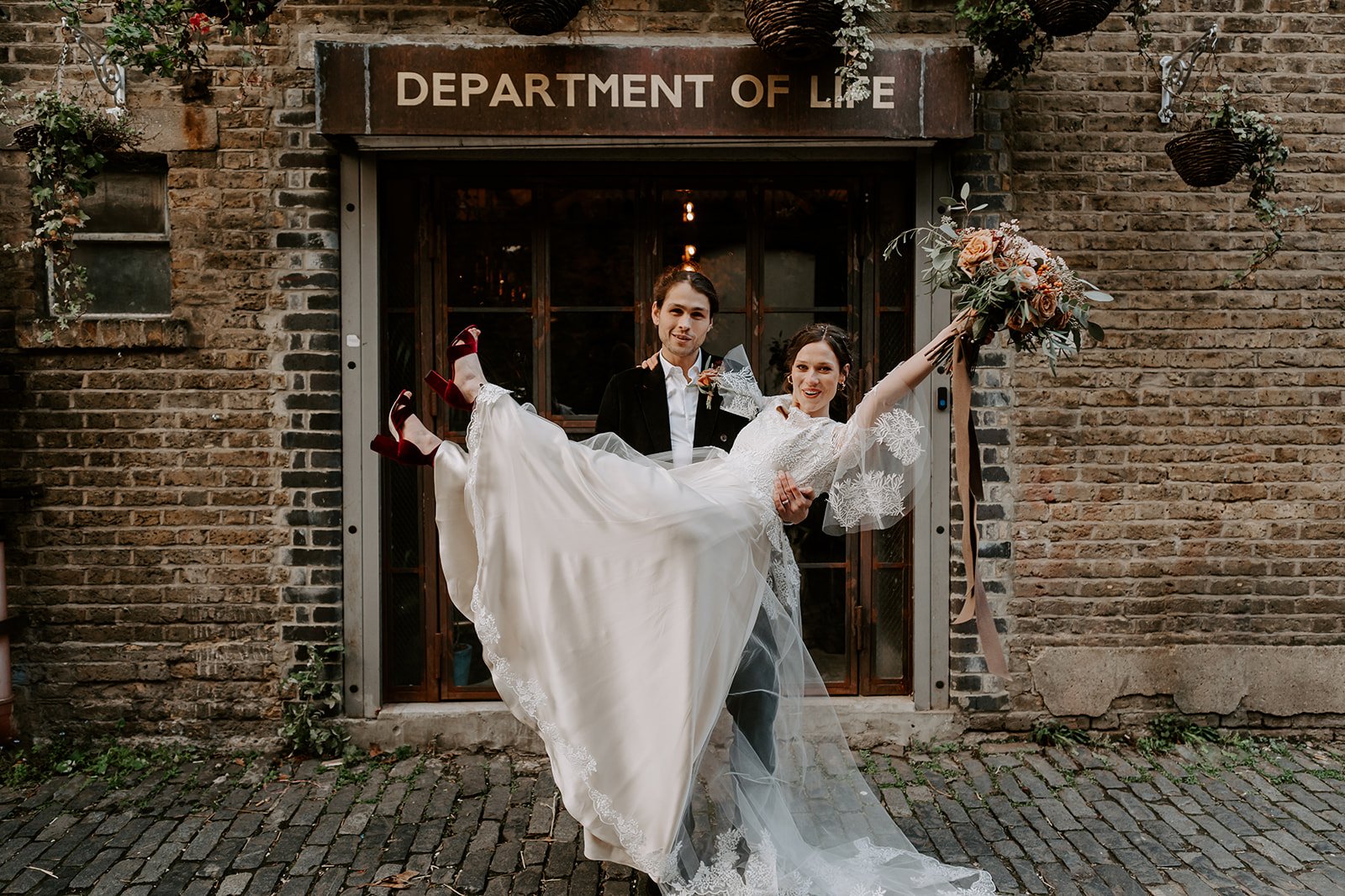 groom holding bride in air outside entrance London Clapton Country Club wedding photography