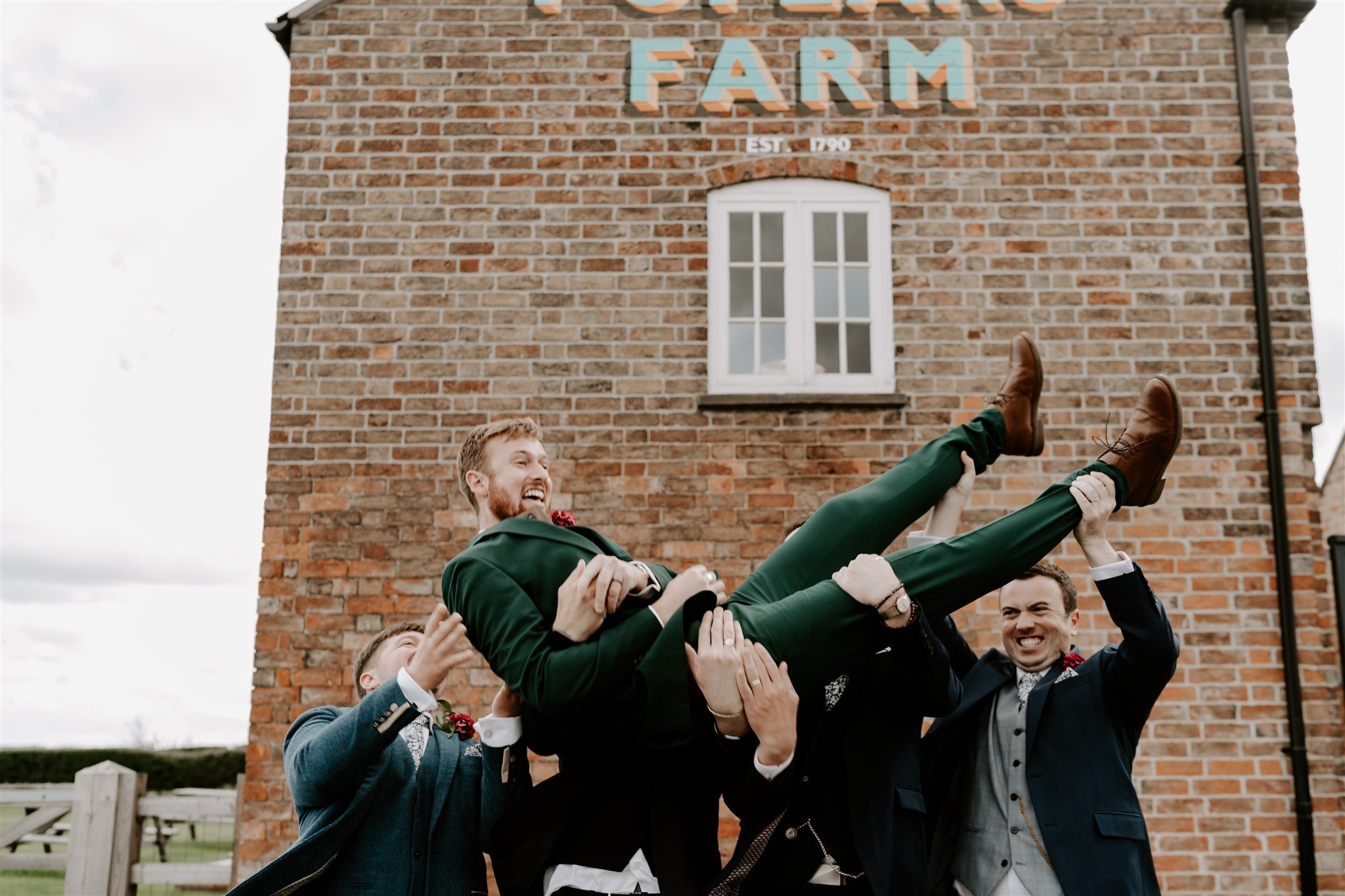 groomsmen throw groom in air Old cow shed wedding leicestershire