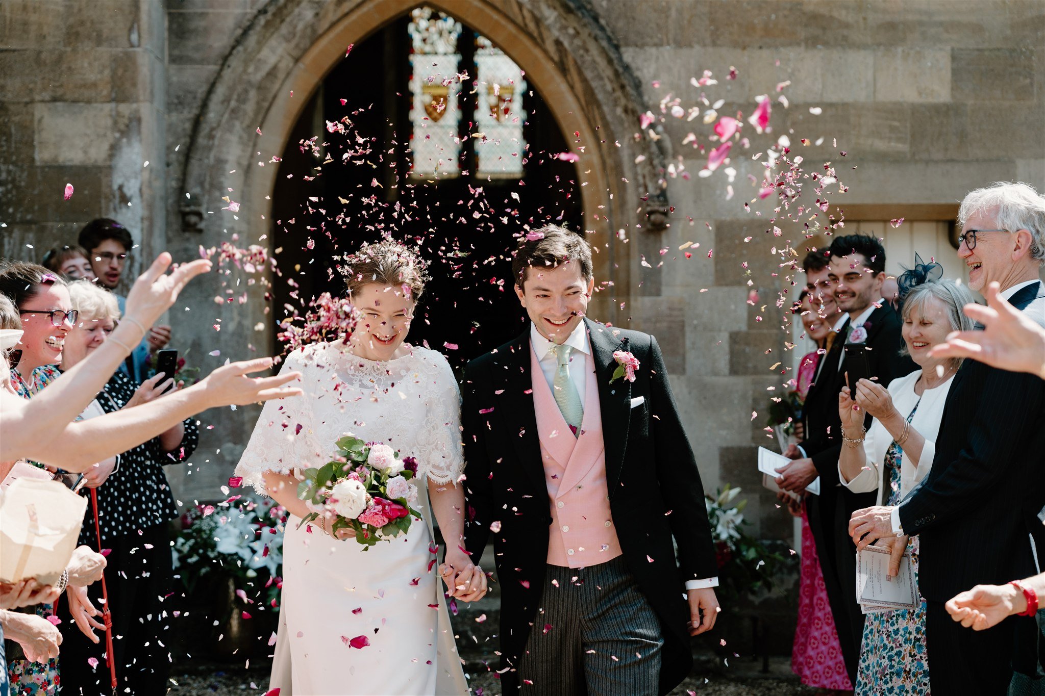Marquee wedding photographer Rutland capturing a joyful couple outside Exton Chapel, Rutland