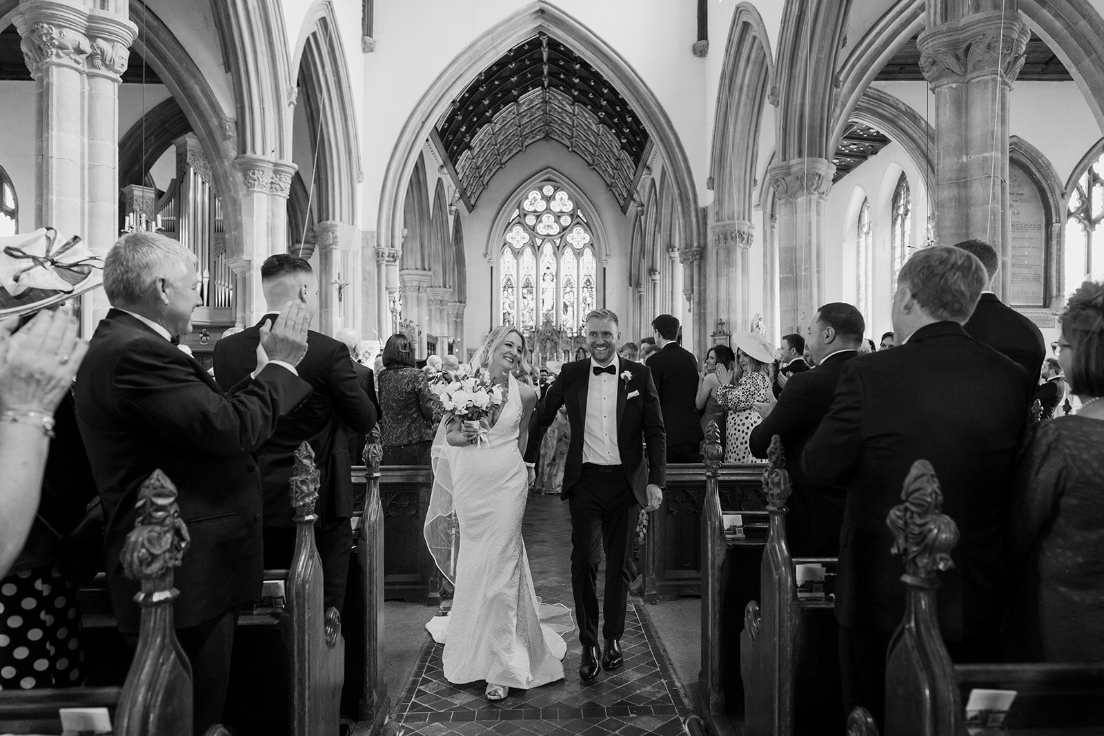 Bride and groom walking back down the aisle after their church ceremony at a black tie wedding in Rutland.