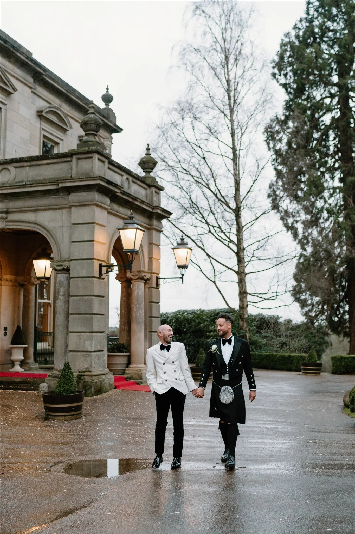 Couple walking hand in hand outside the entrance of Kilworth House during a black tie wedding, photographed in a natural documentary style.