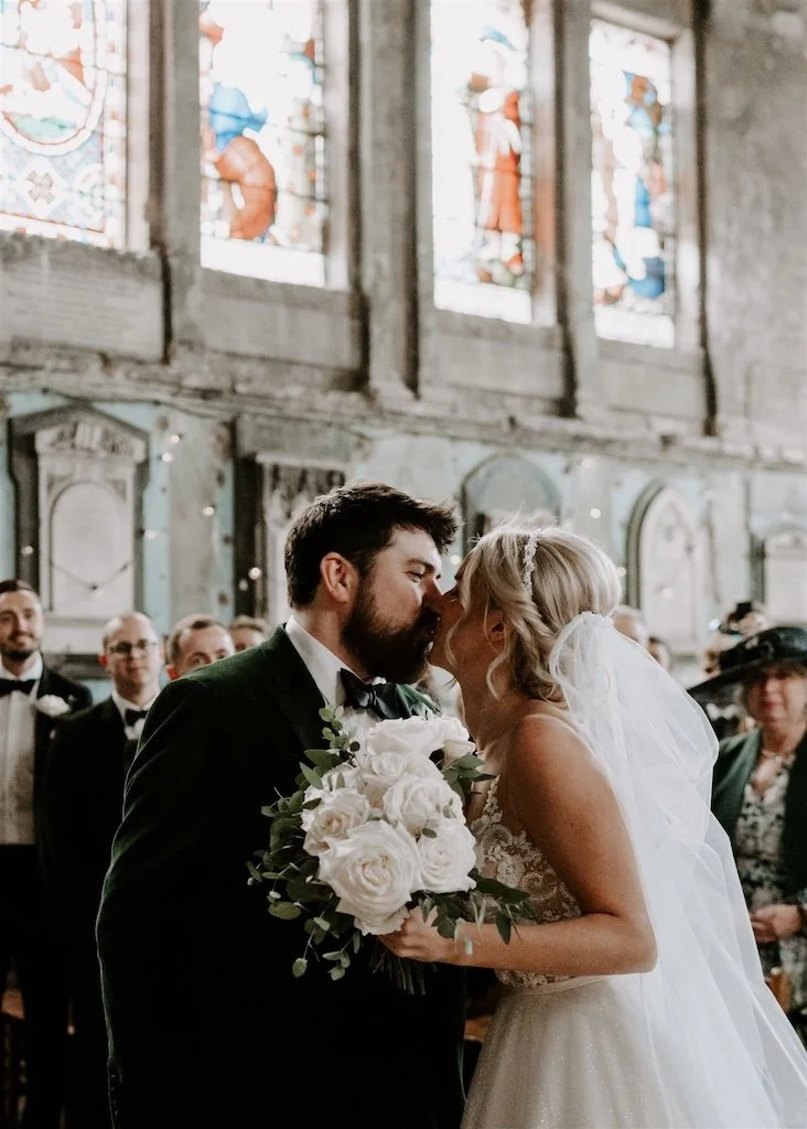 Bride and groom sharing their first kiss during a wedding ceremony in Asylum Chapel London