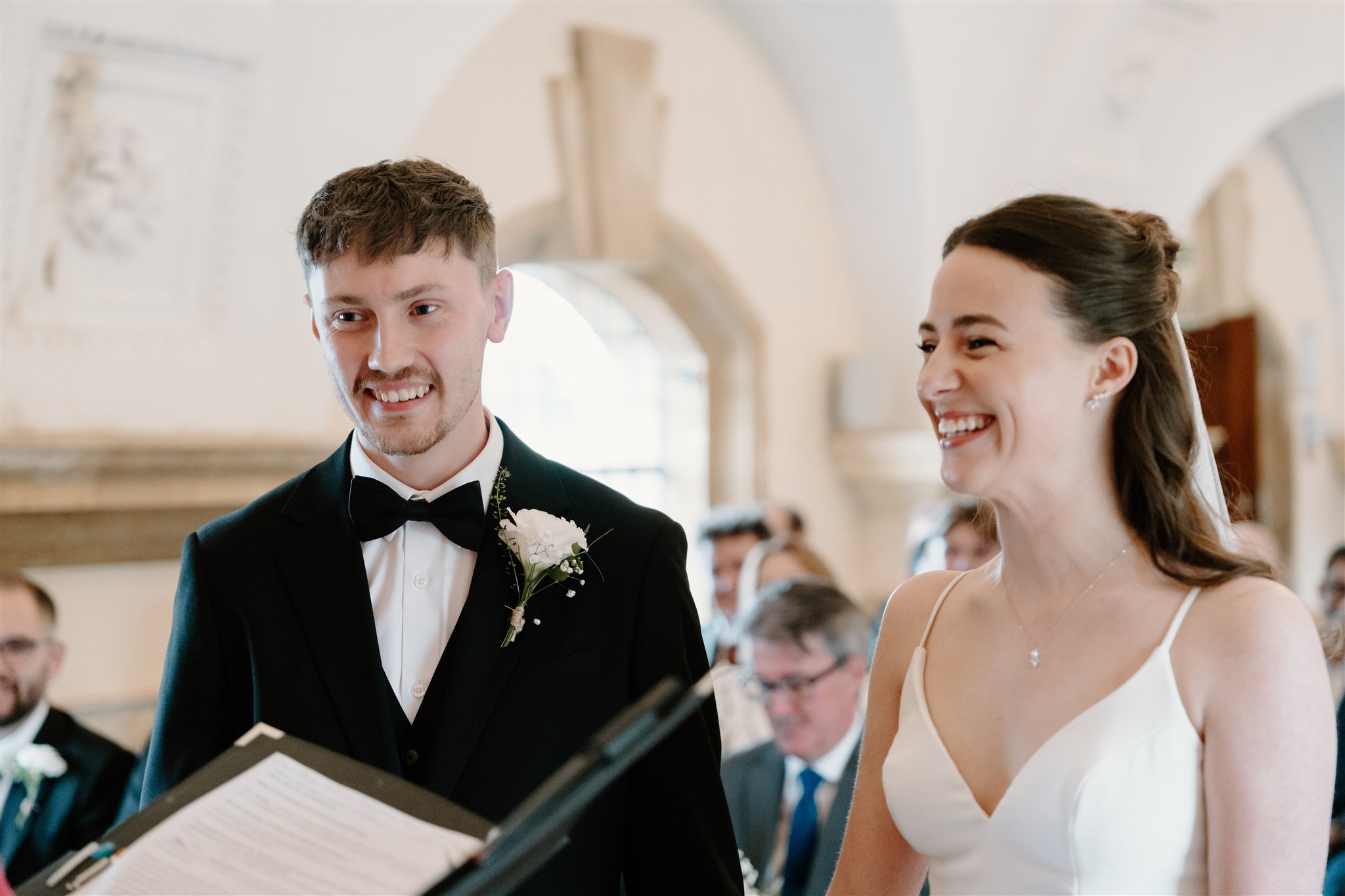 Bride and groom smiling during their wedding ceremony inside Normanton Church, photographed in a documentary style.