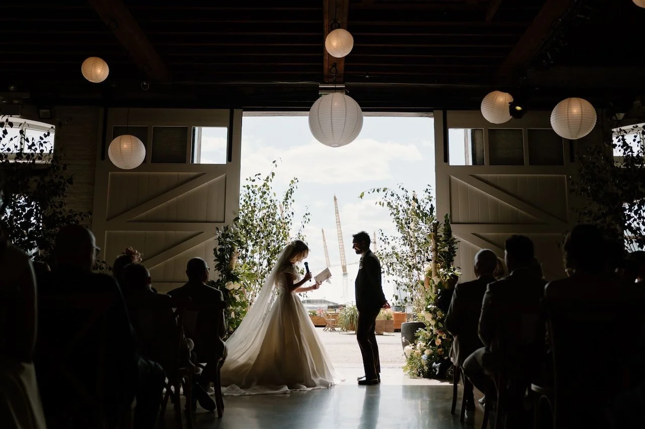 Bride and groom exchanging vows at Trinity Buoy Wharf with the Thames and Docklands in the background