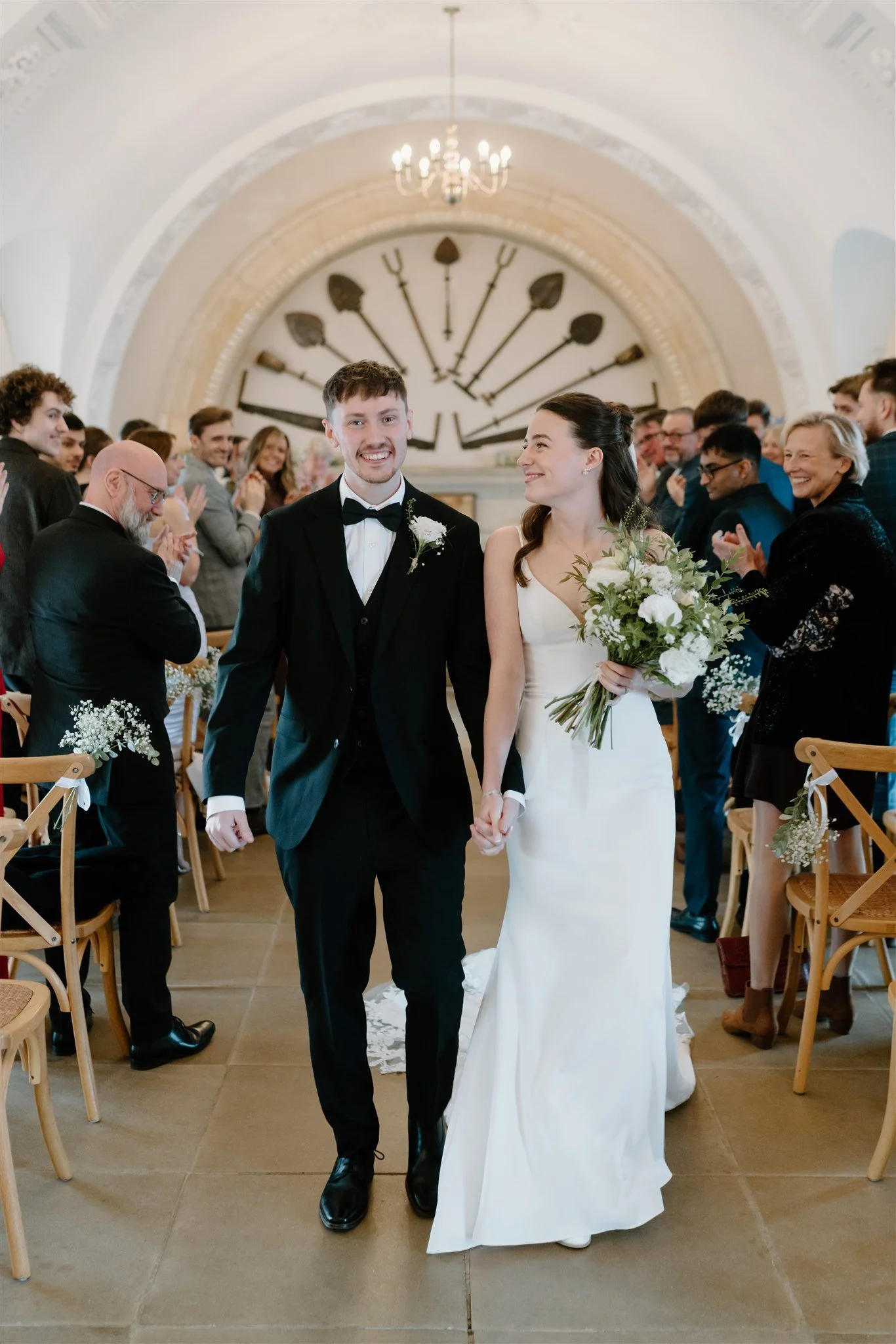 Newly married couple walking back down the aisle at Normanton Church as guests applaud during their wedding ceremony.