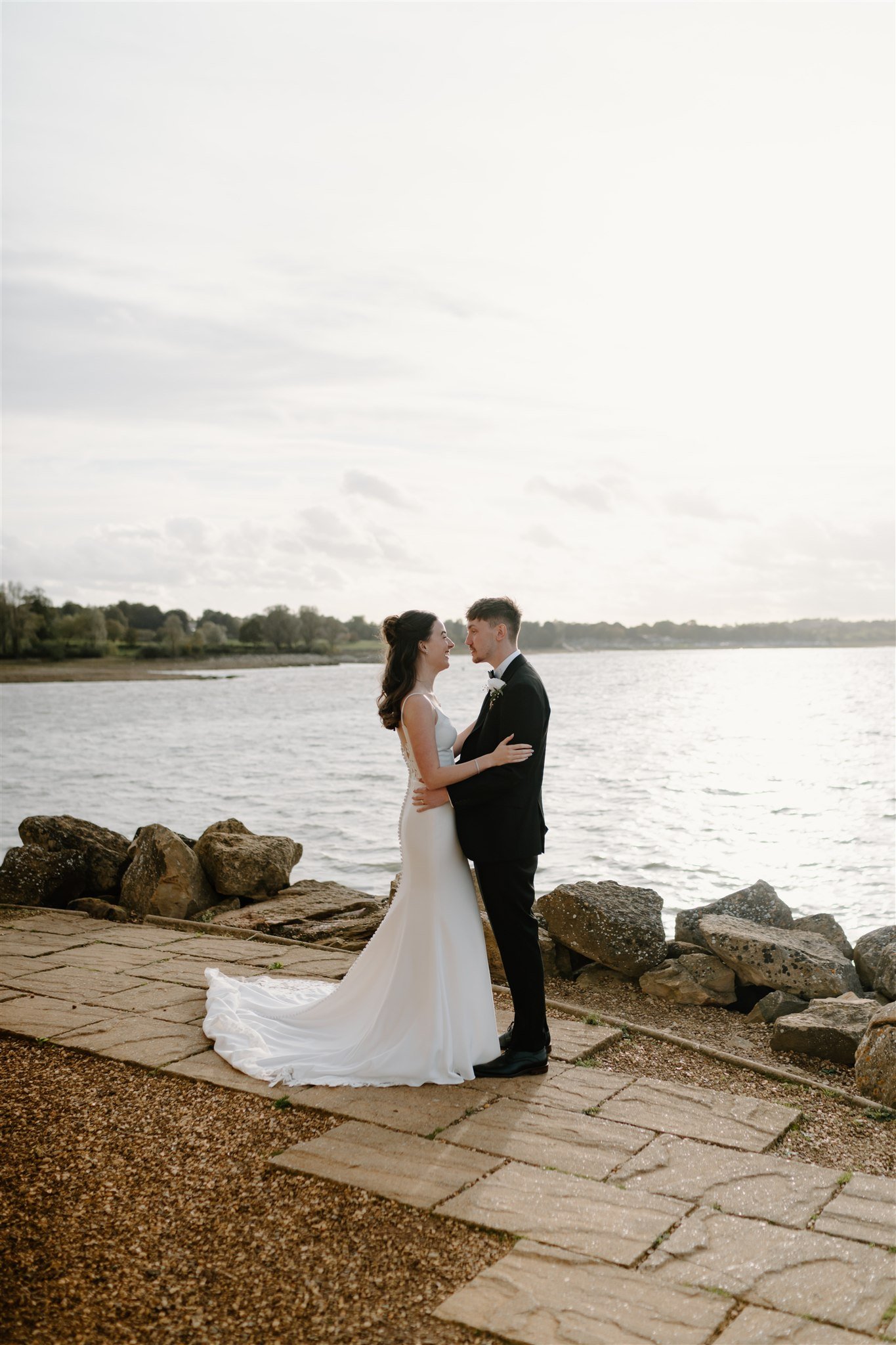 Bride and groom standing together by the water at Normanton Church after their intimate wedding ceremony