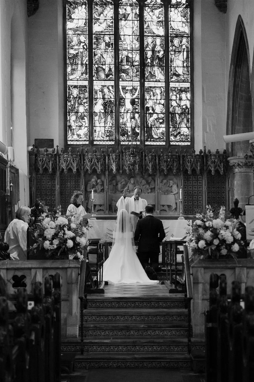 Black and white photograph of a Stamford All Saints church wedding ceremony with couple at the altar.