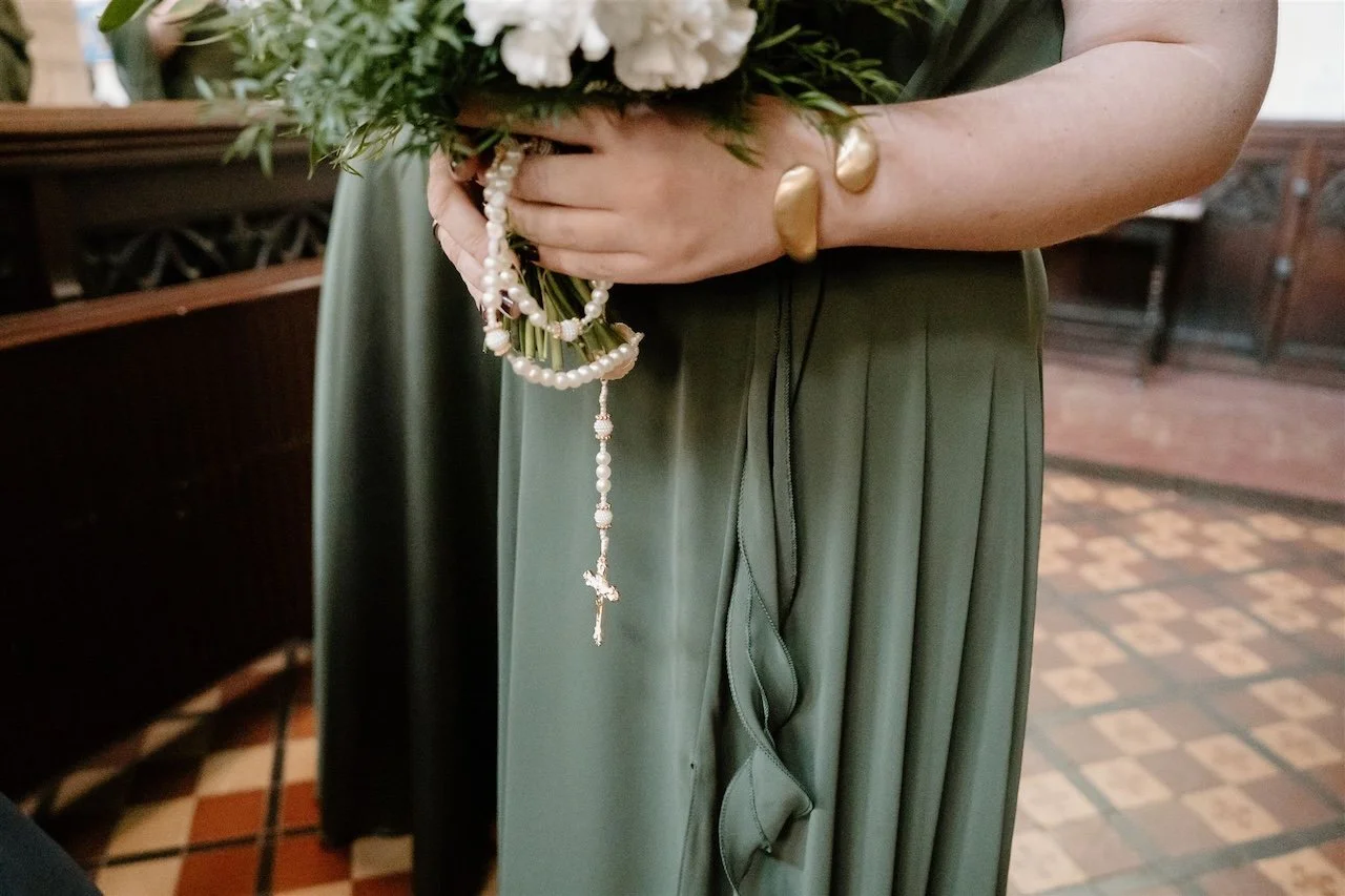 Bridesmaid holding bouquet with rosary beads during a Stamford church wedding with Brazilian traditions
