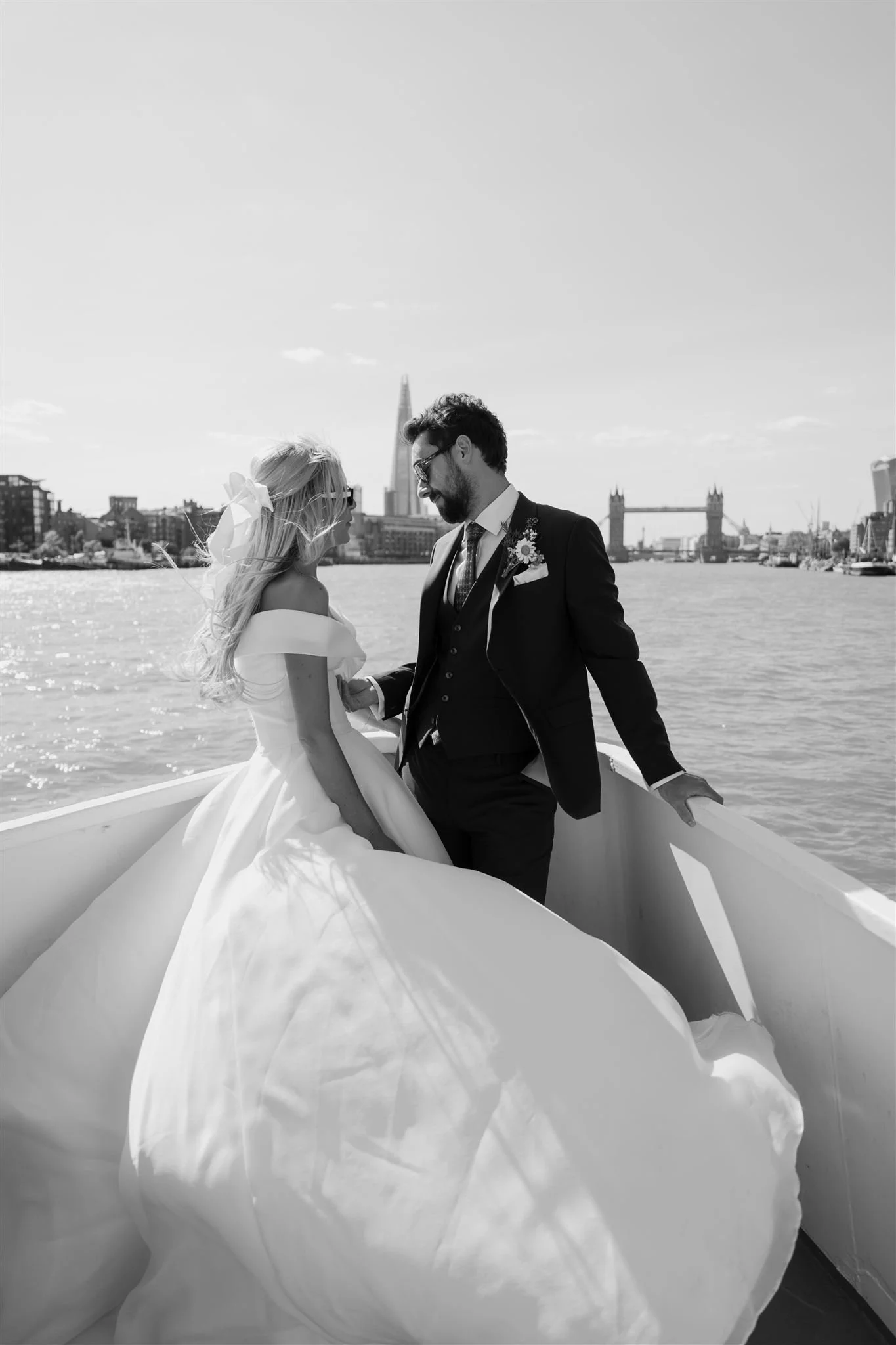 Bride and groom on a boat on the River Thames with the London skyline behind them