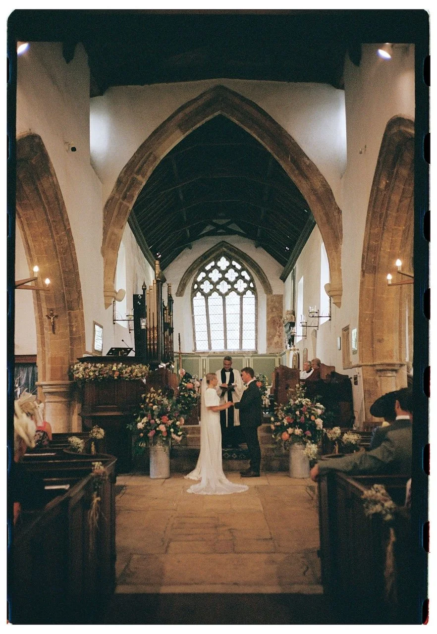 Wedding ceremony inside St James Church Gretton, bride and groom exchanging vows, photographed on 35mm film in Northamptonshire