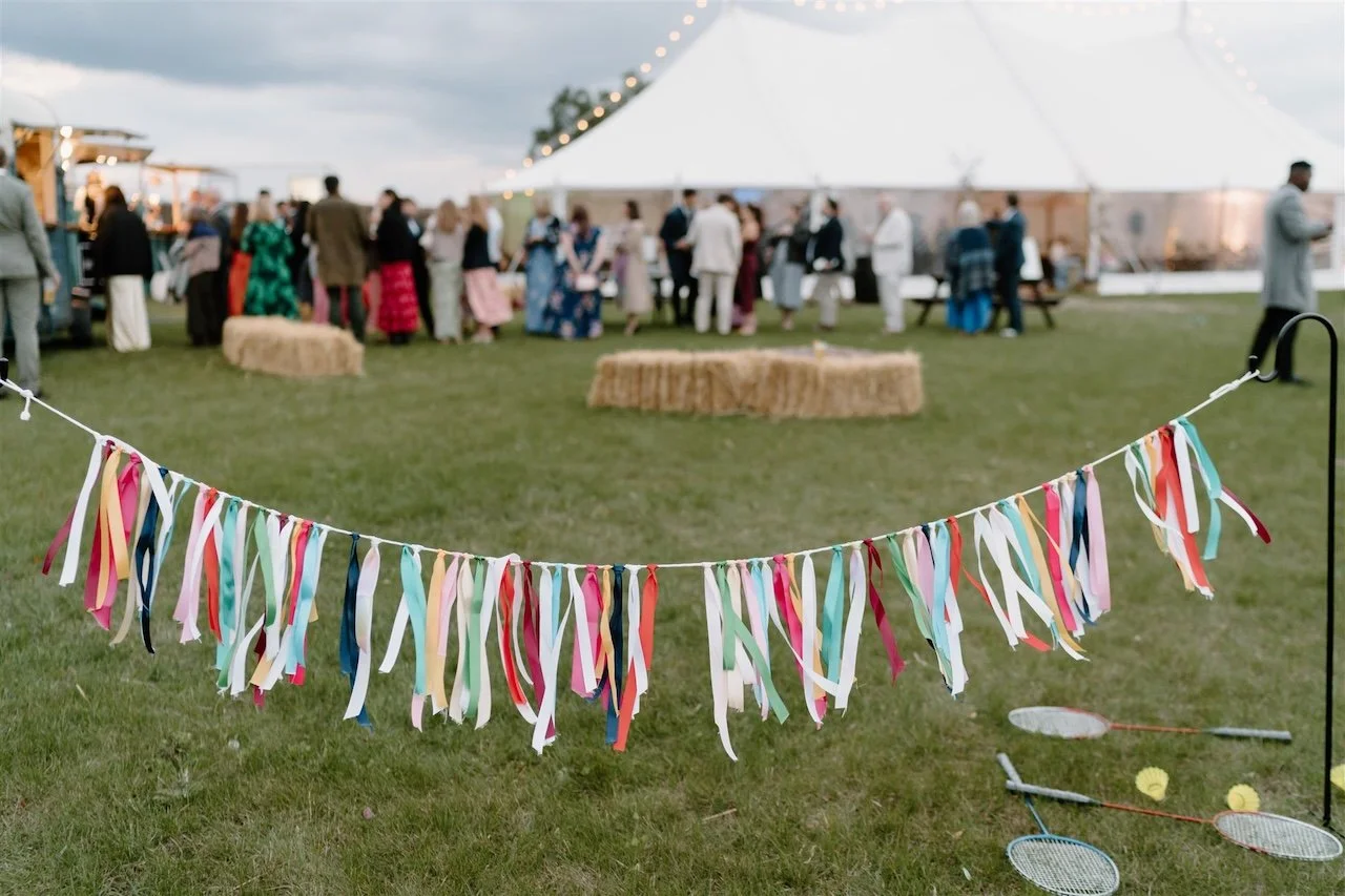 Colourful ribbon bunting and lawn games in front of the sailcloth marquee at Ed’s Hill Top Tent wedding venue in Stamford