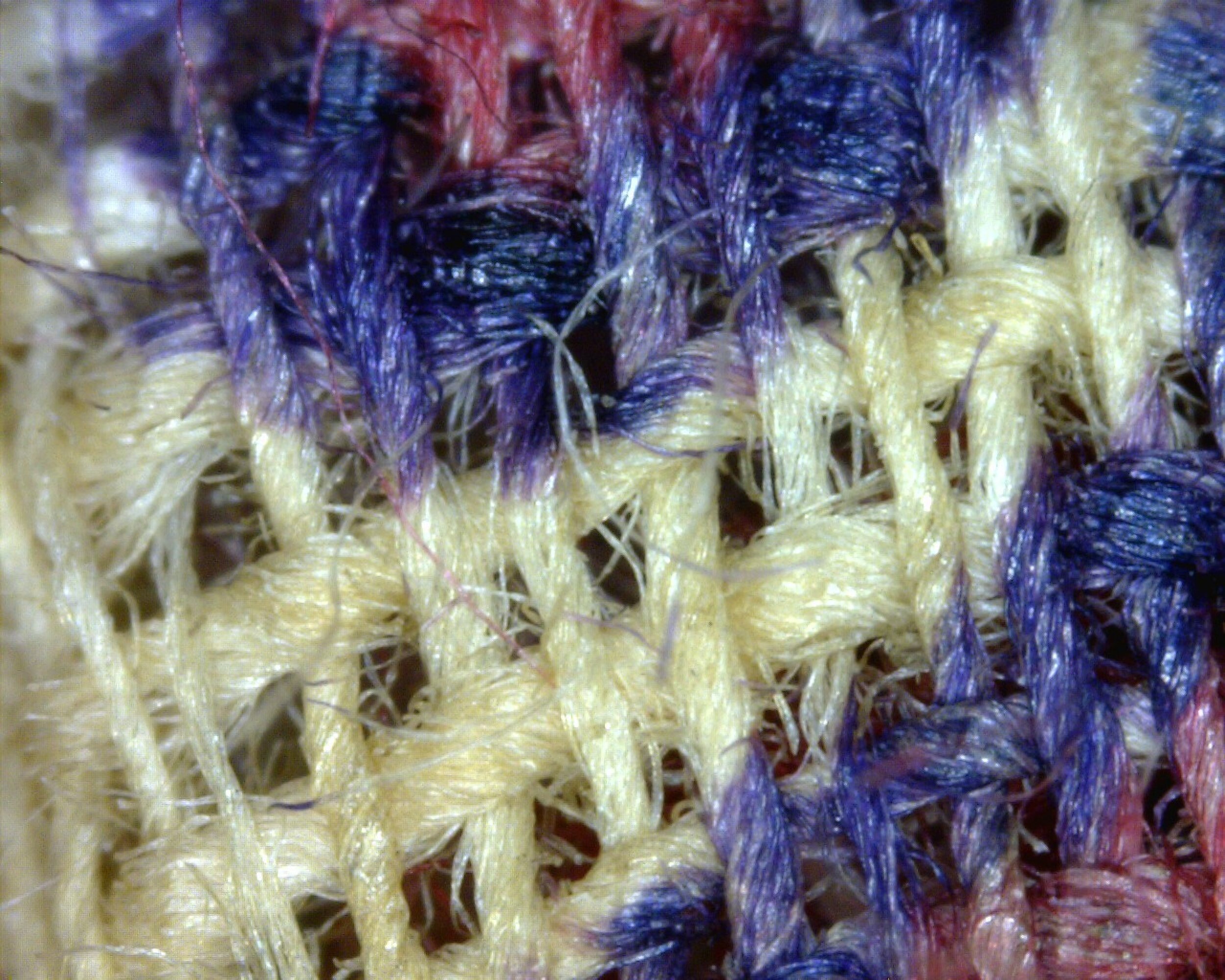 This micro image of the pocket's exterior quilted fabric illuminates Z-spun yarns that have been woven into a 2/1 S-twill. Although much of the woven fabric has disintegrated over time, several remnants still remain. The fabric has an ivory ground