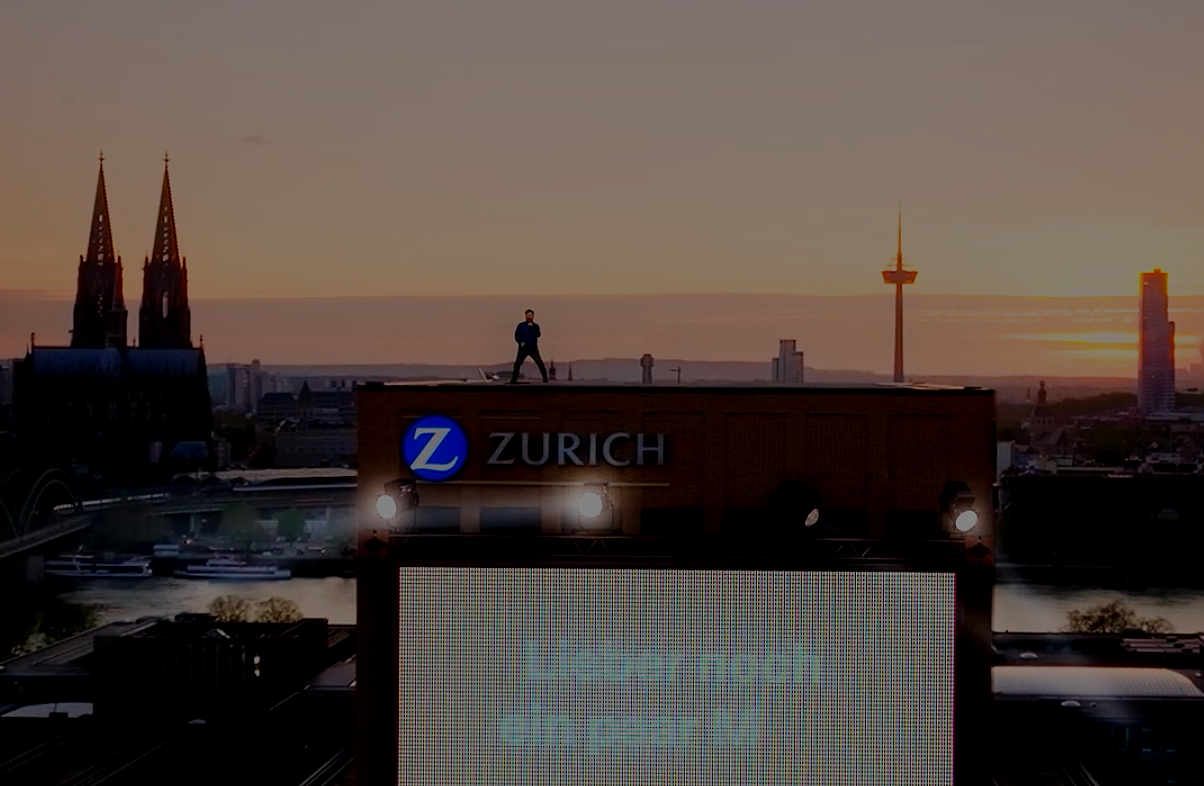 Ein Commerial für Zurich, bei dem ein Sänger auf dem Gebäude der Versicherung steht
