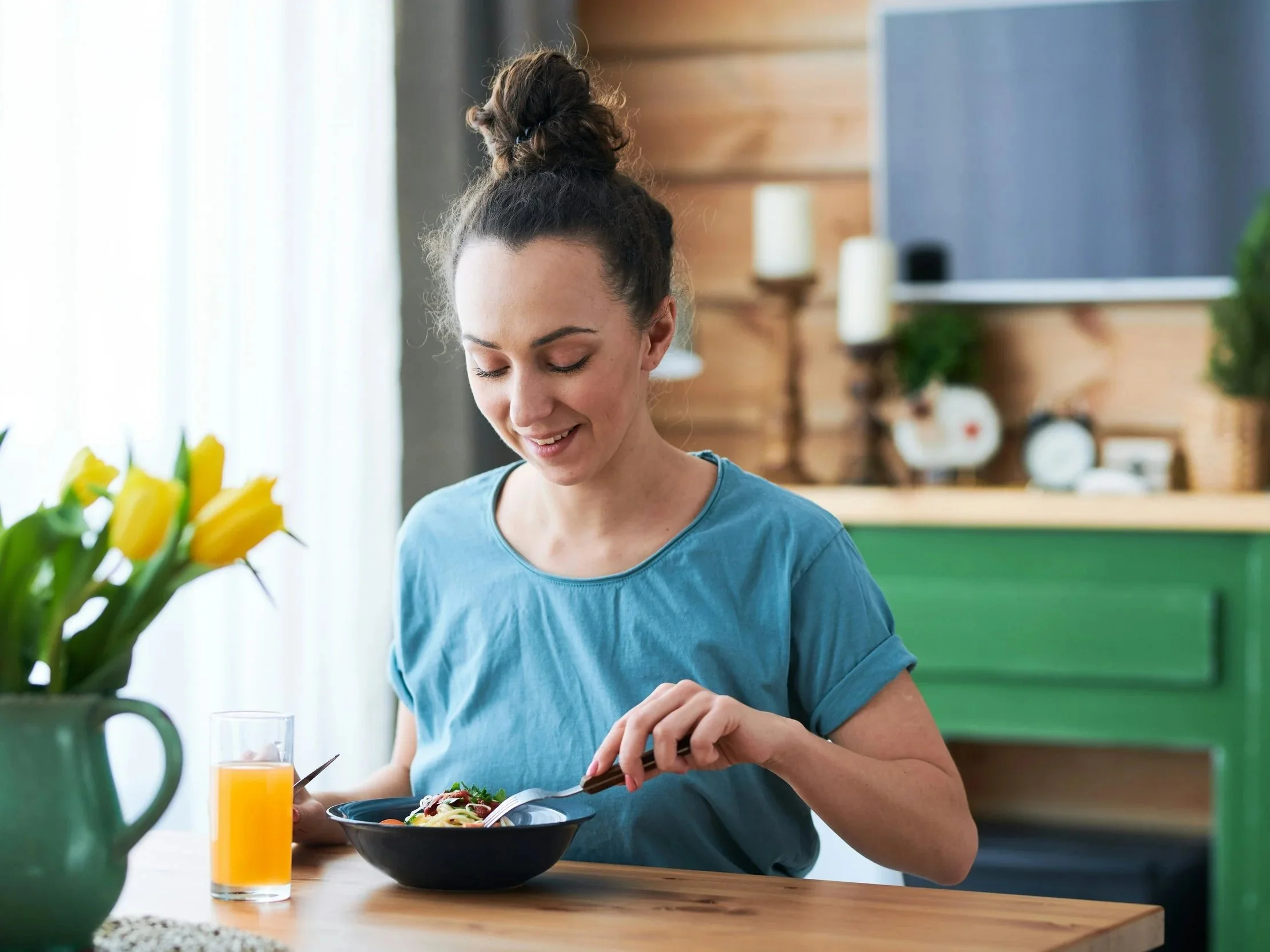 Woman enjoying a lunch of chicken, rice, and vegetables at home.