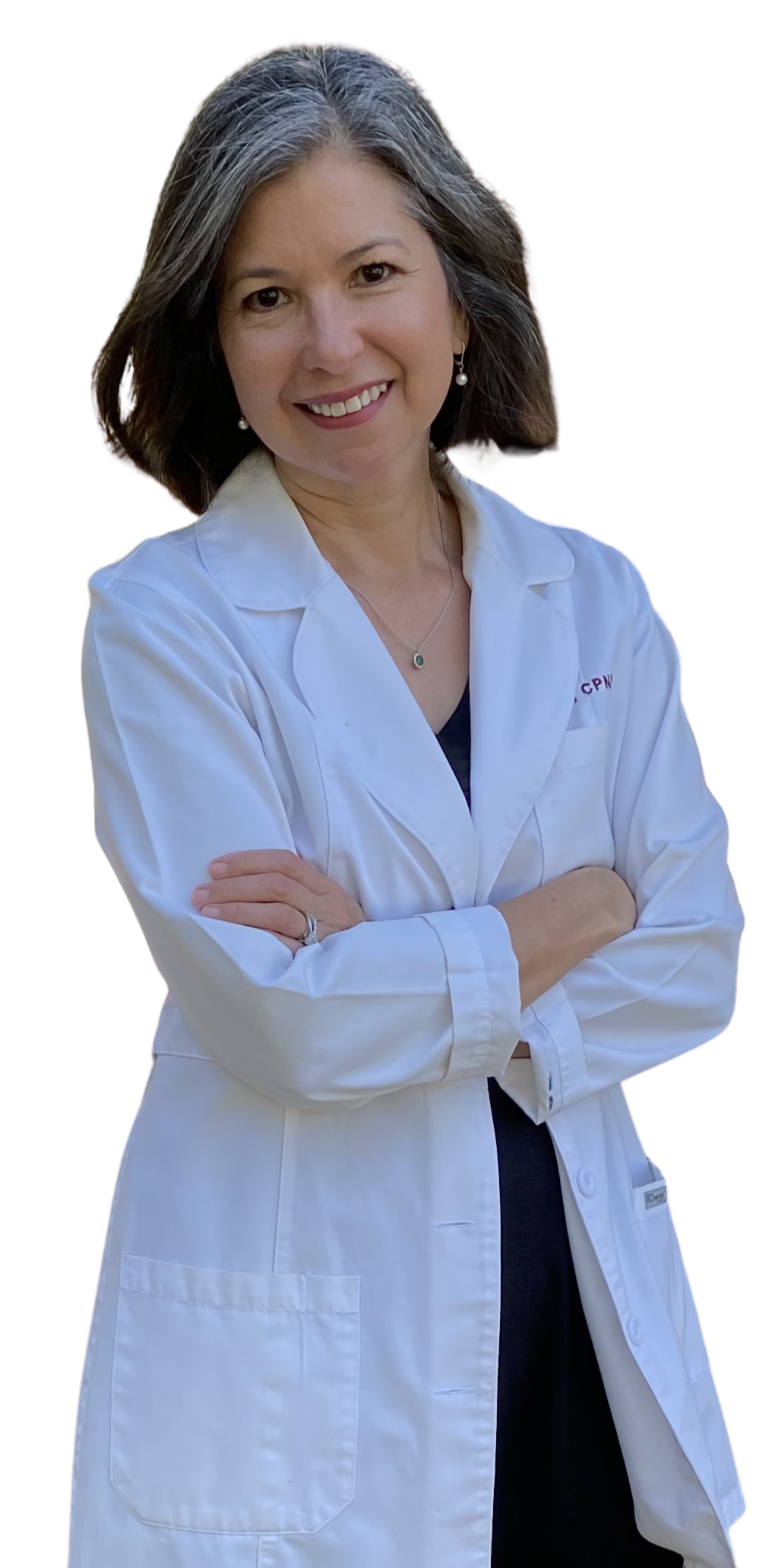 A woman wearing a white medical coat with folded arms, smiling, with dark hair with gray streaks, and earrings, in an outdoor setting.
