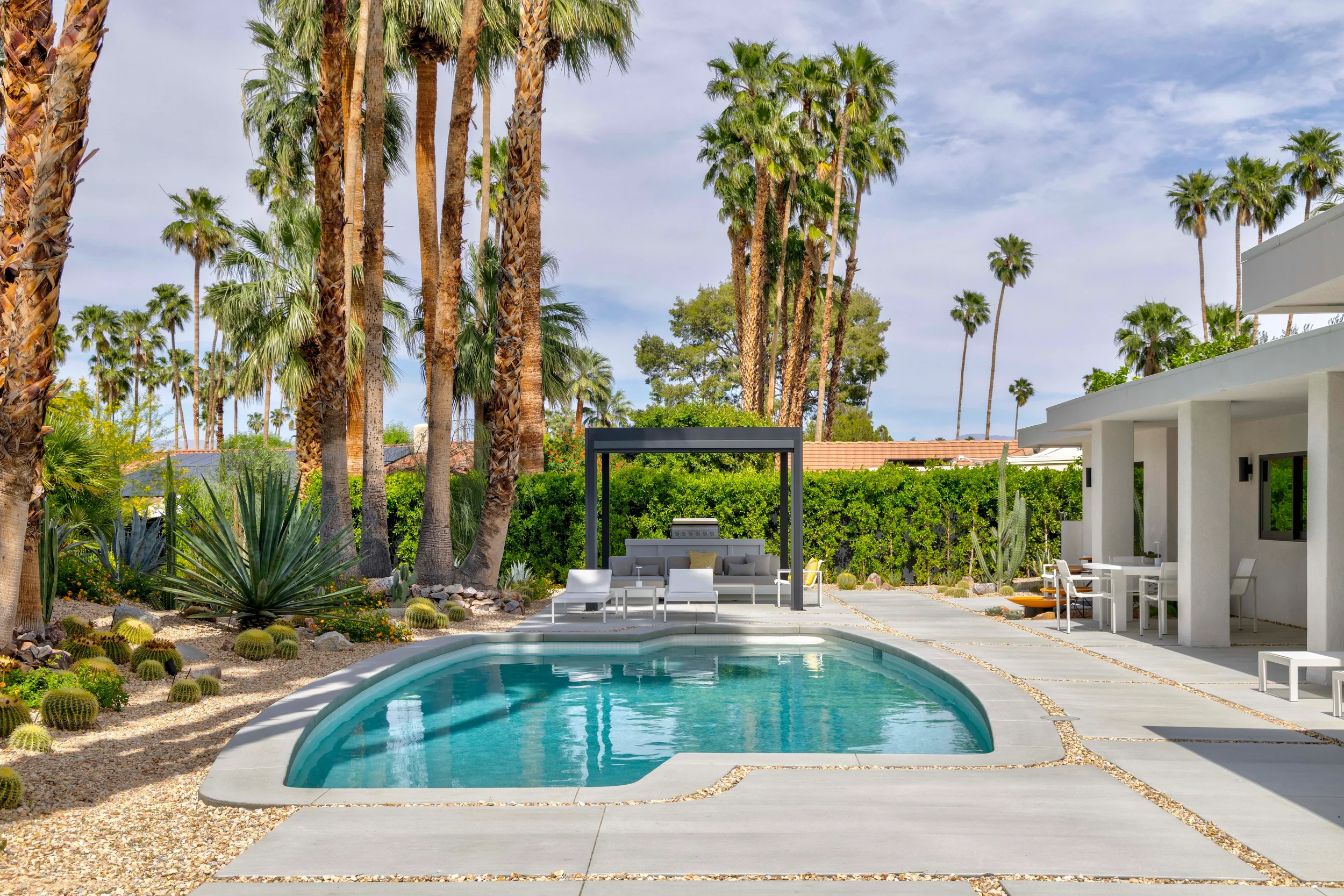 Indian Canyons backyard with modern desert pool landscape, geometric paving, cacti, and palm trees creating a resort-style outdoor space.