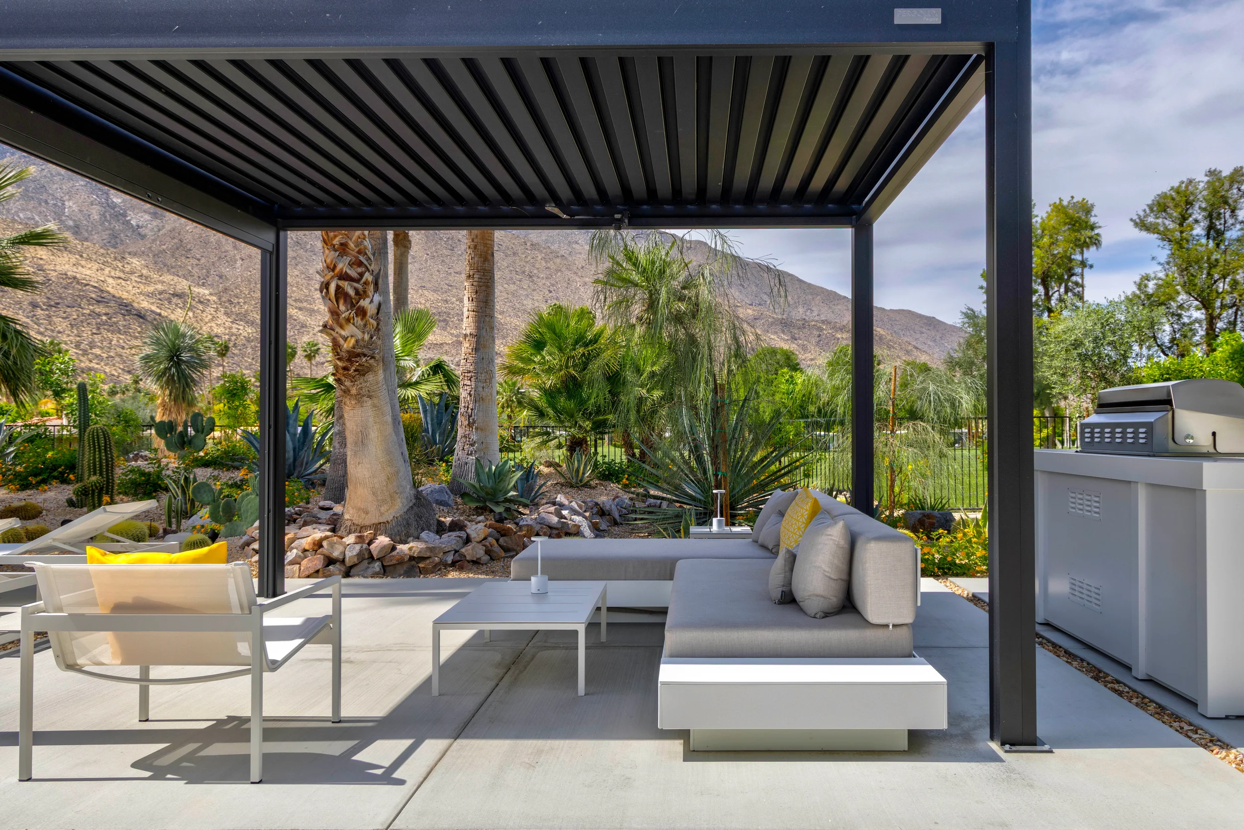 Outdoor living space in Indian Canyons Palm Springs featuring modern pergola, lounge seating, and desert planting with mountain backdrop.