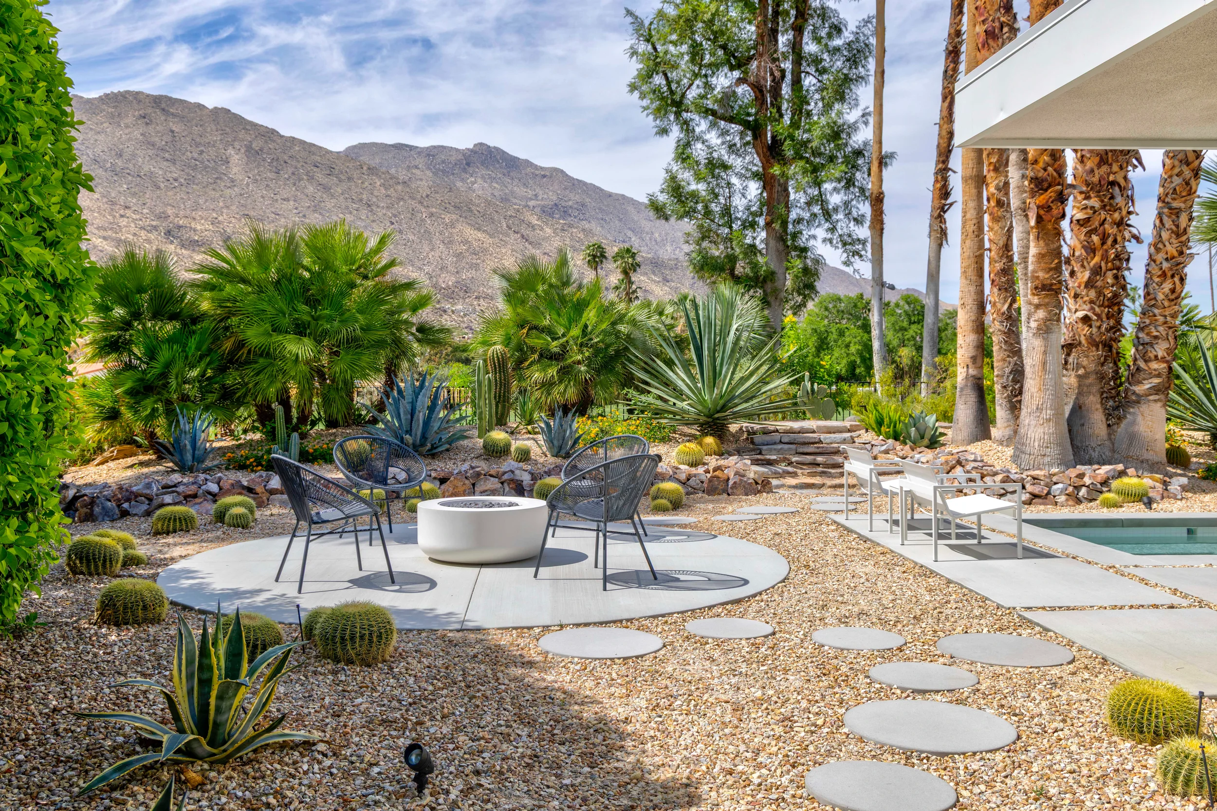 Modern desert fire pit seating area in Indian Canyons Palm Springs with circular concrete pad, gravel, and drought-tolerant plantings.