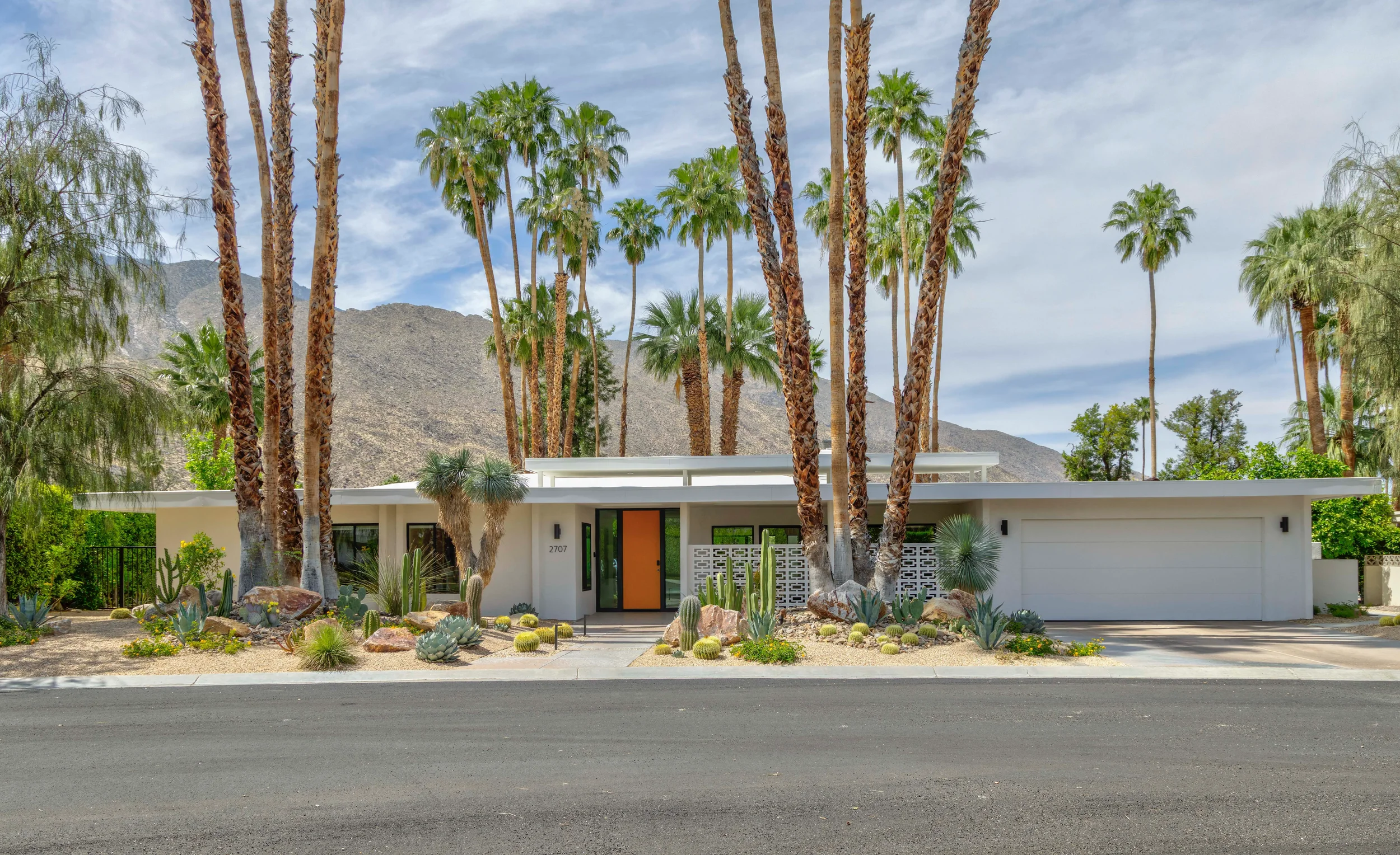 Modern desert home front elevation in Indian Canyons Palm Springs with layered cactus planting, palms, and mountain backdrop.