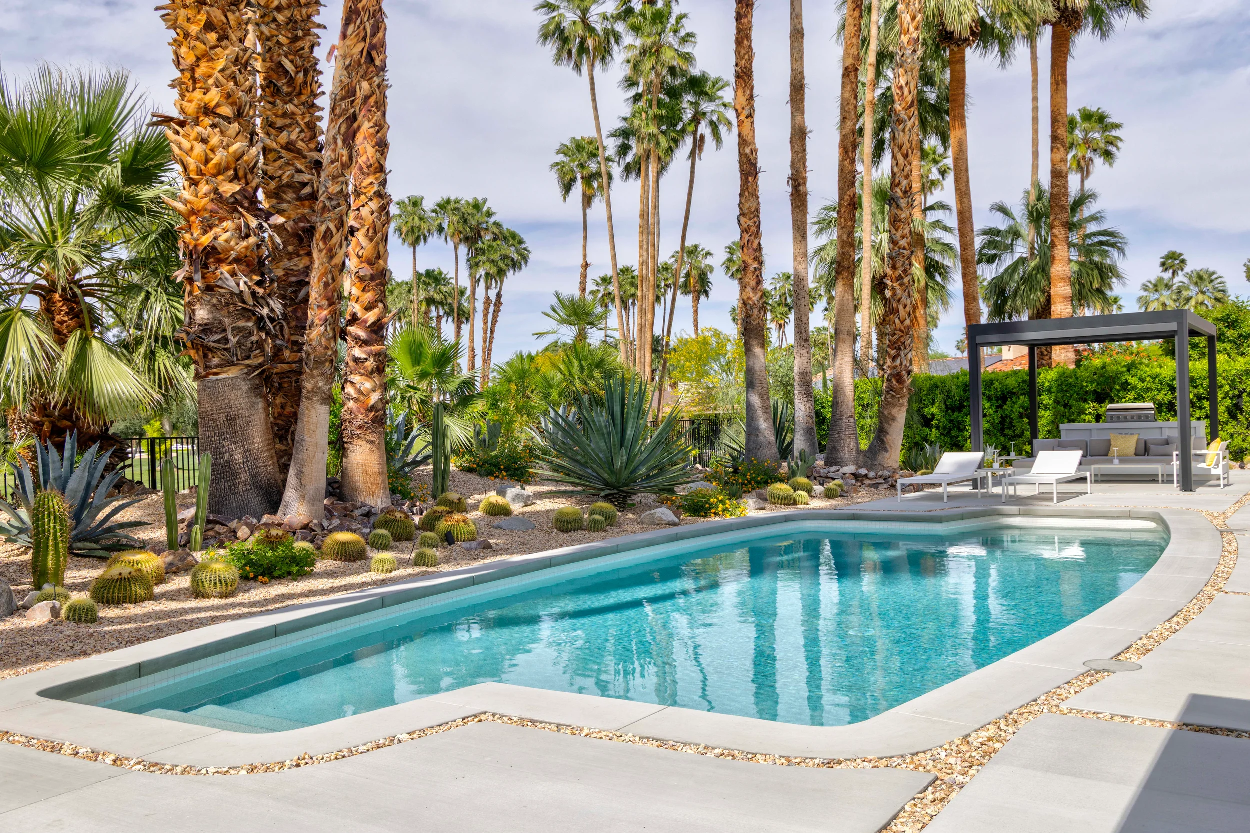 Modern desert pool landscape in Indian Canyons Palm Springs with palm trees, agave, cacti, and resort-style outdoor living.