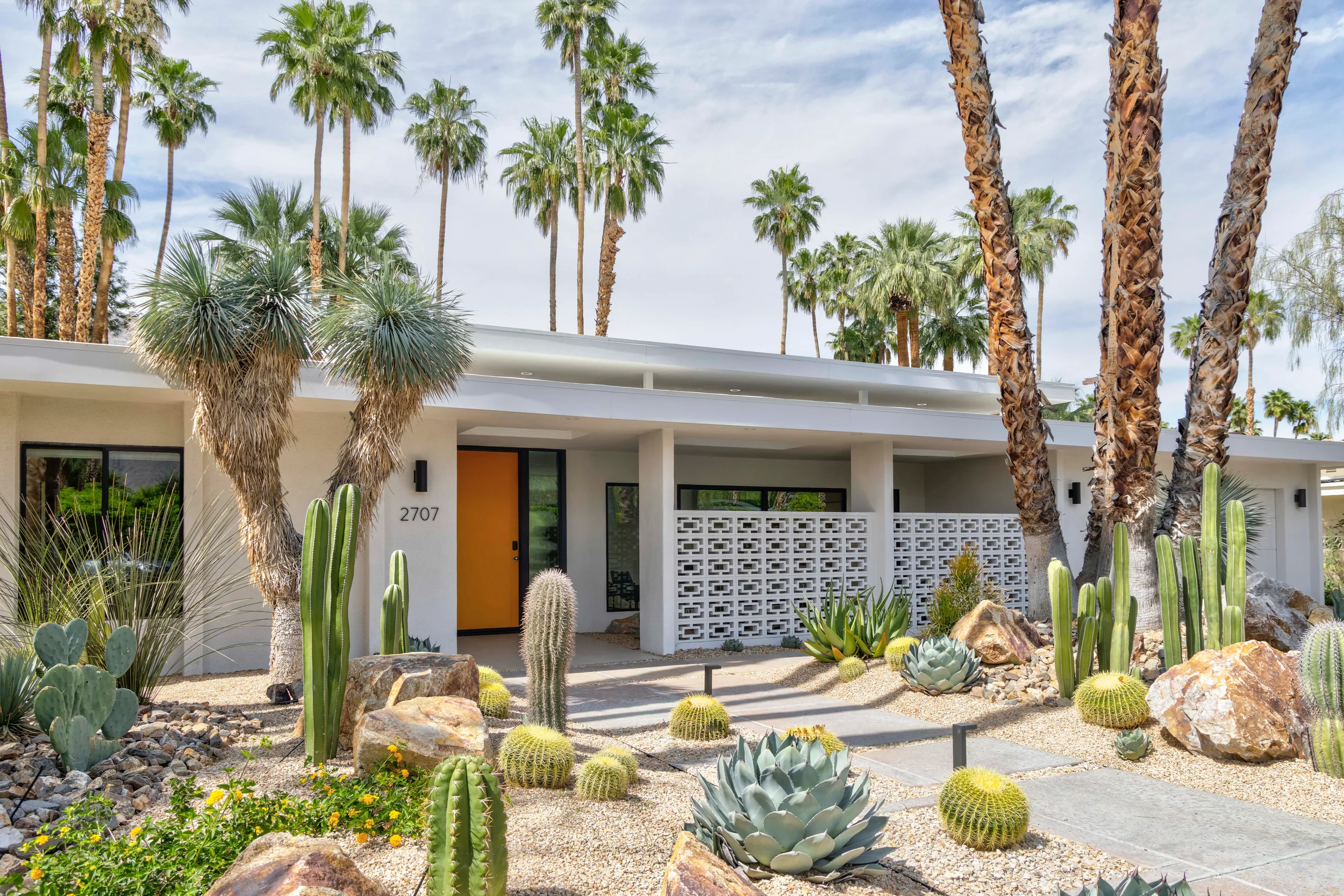 Modern desert landscape front entry in Indian Canyons, Palm Springs with concrete walkway, sculptural cacti, agave, and breeze block wall.
