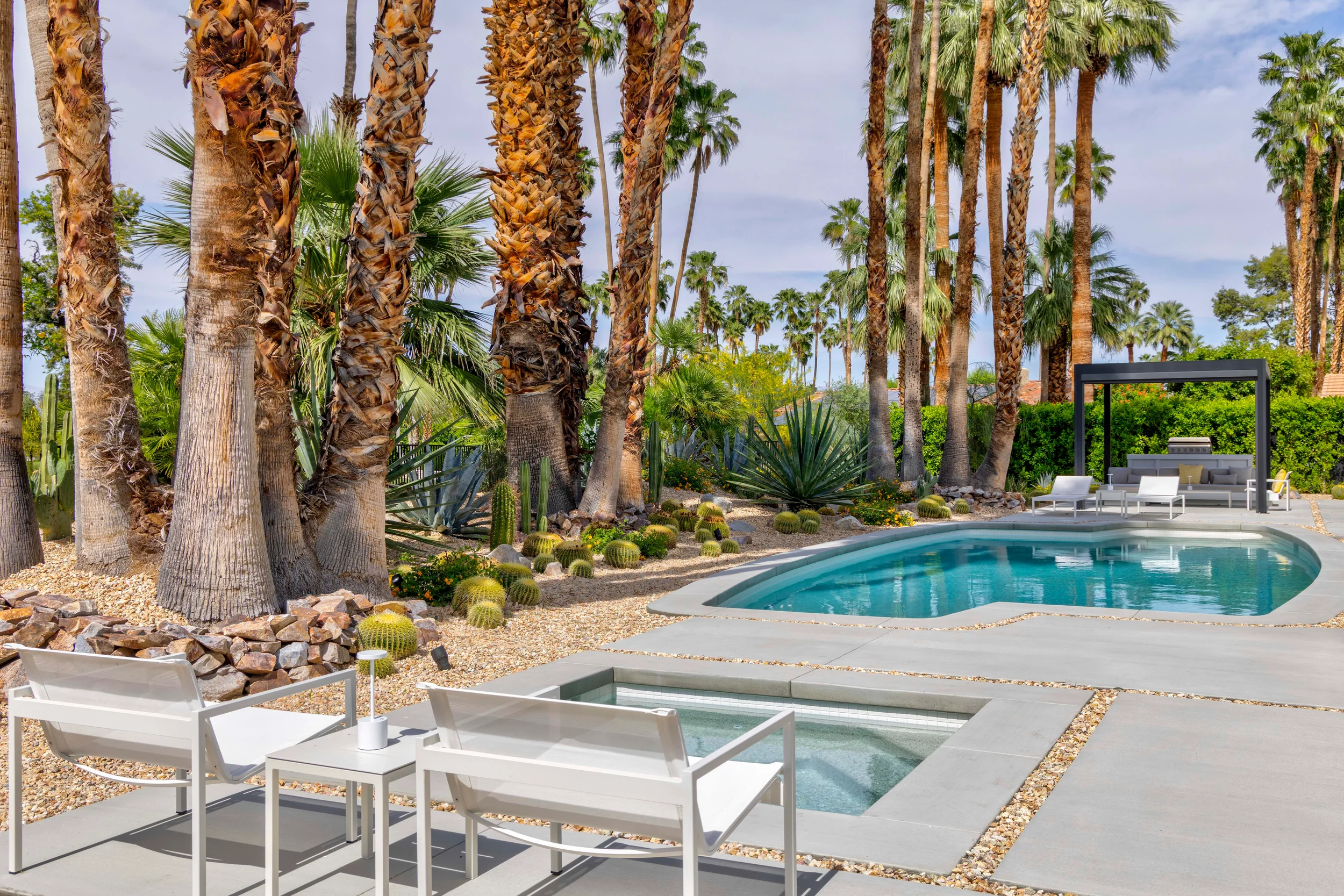 Palm Springs modern desert pool and spa with lounge seating, geometric concrete paving, and palm trees in Indian Canyons.