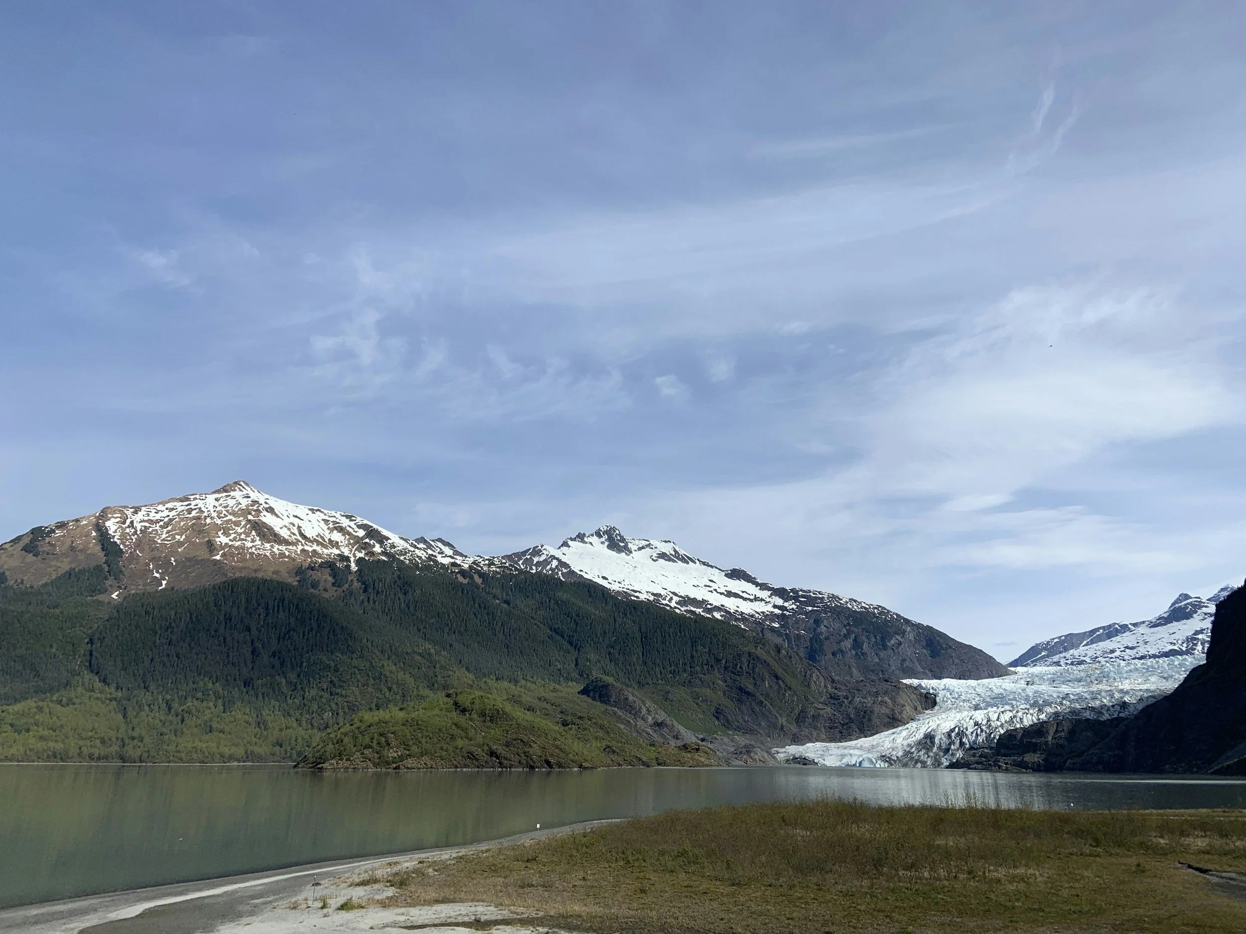 Glacier and calm blue water under bright July daylight in Alaska