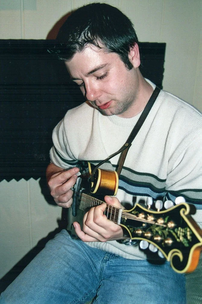 A young man with black hair playing an acoustic guitar.
