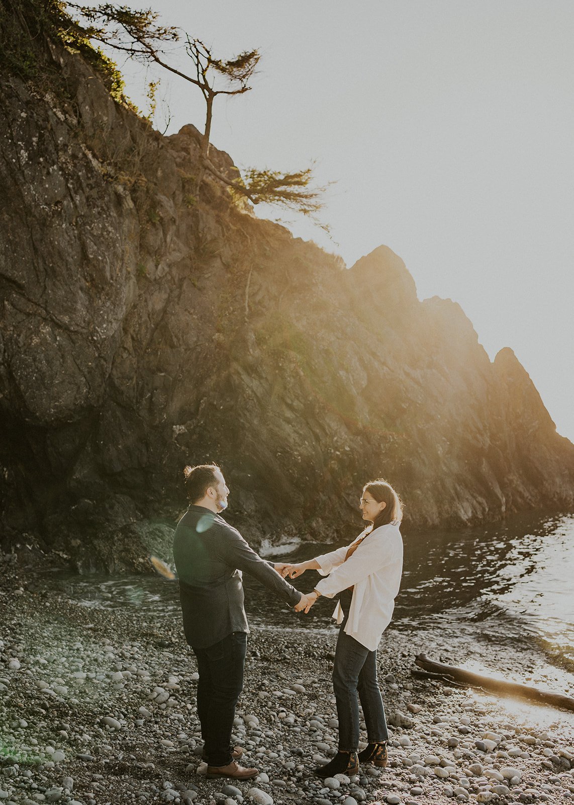 couple holding hands at deception pass state park along rocky coastline
