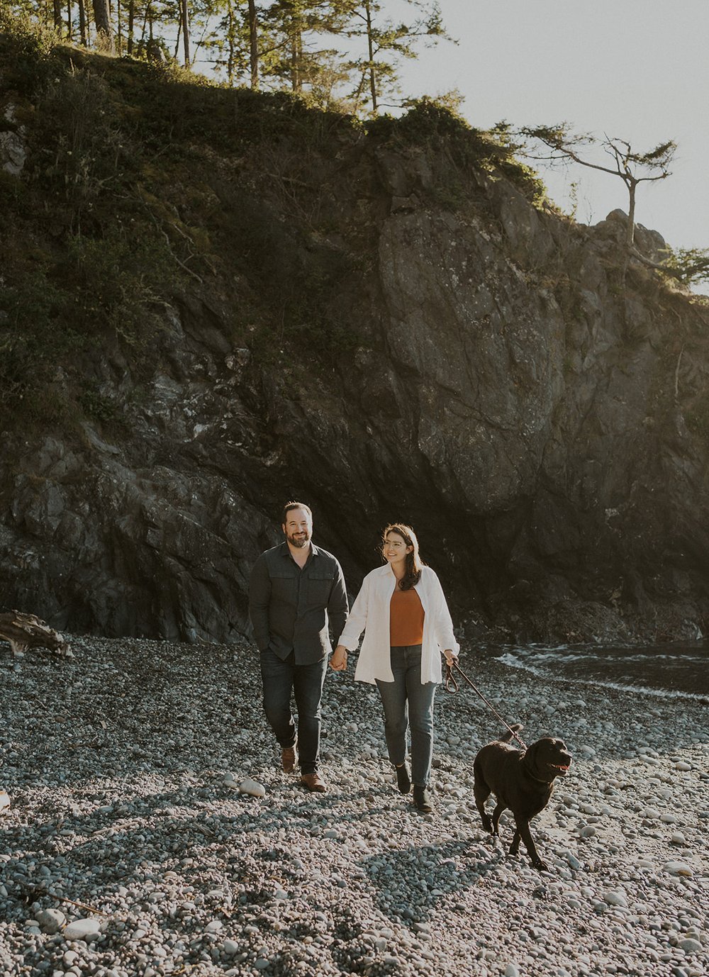 couple holding hands at deception pass state park along rocky coastline