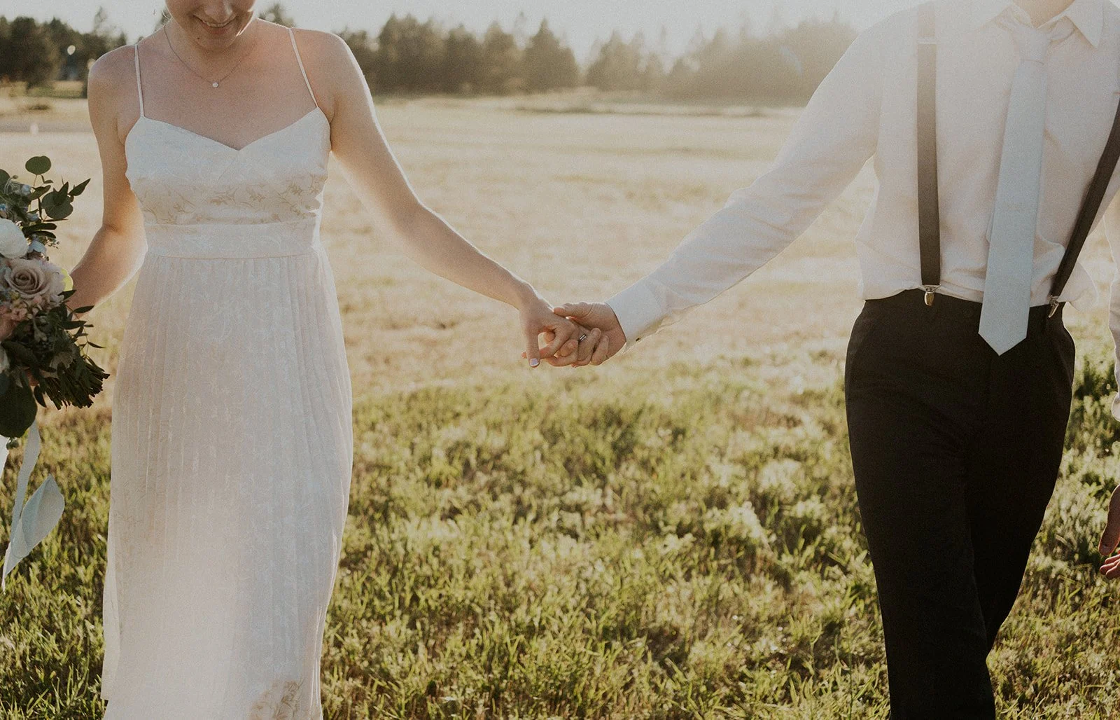 bride and groom holding hands at sunset in spokane