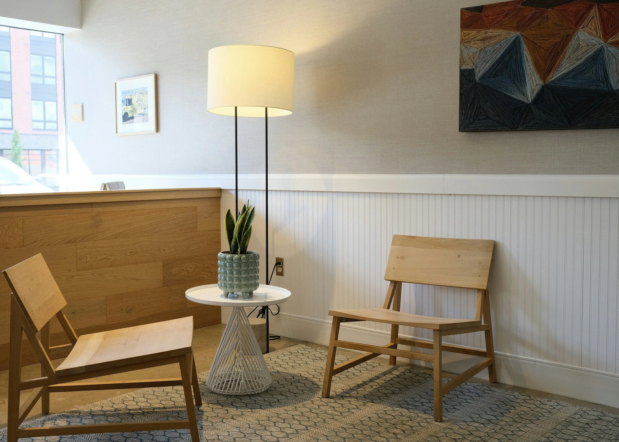Calm therapy office interior with wooden chair, floor lamp, and plant, representing a safe and welcoming space for Brainspotting consultation in Michigan and worldwide with Emily Perraut