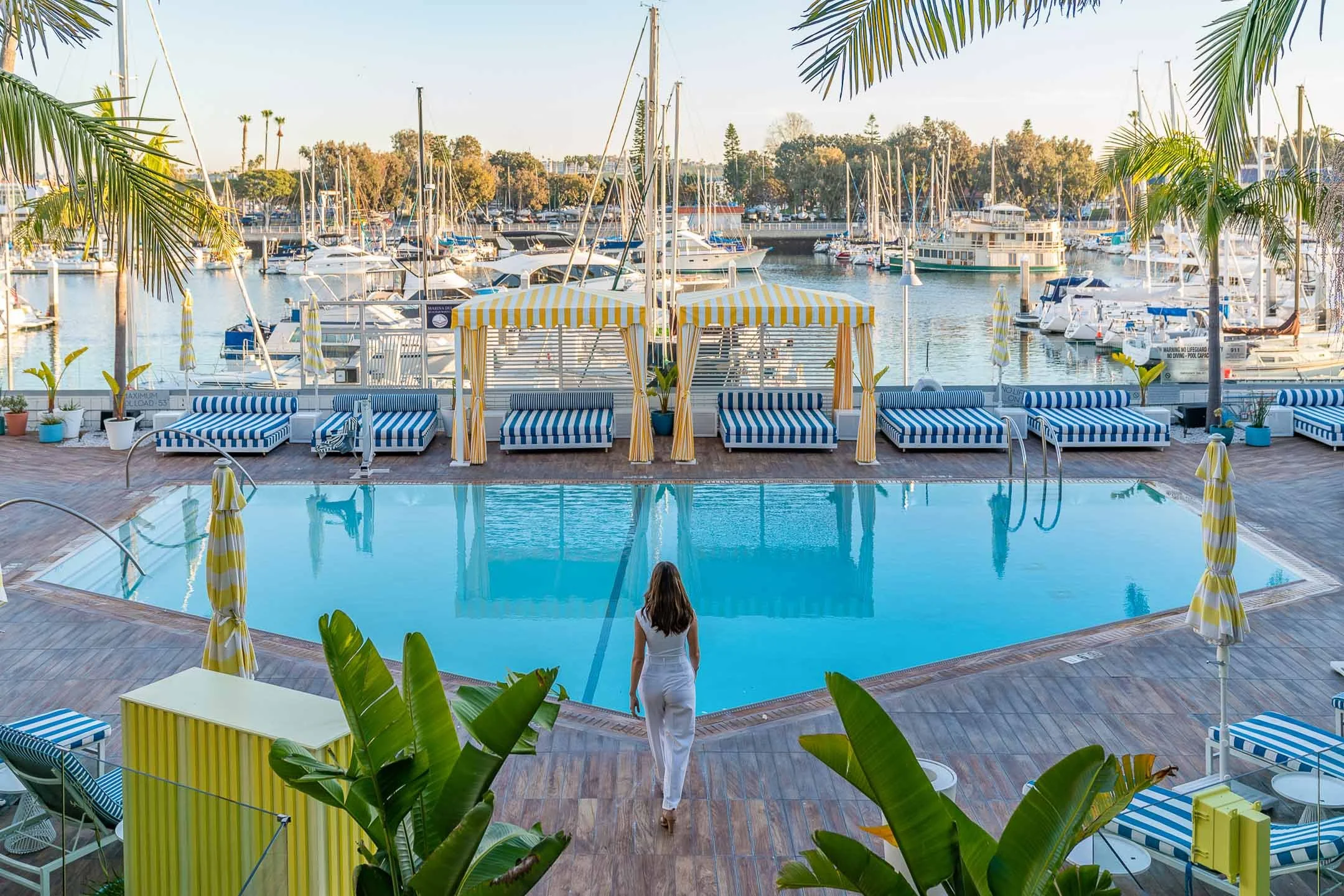 Model wearing white walking towards outdoor pool in Marina del Rey Hotel