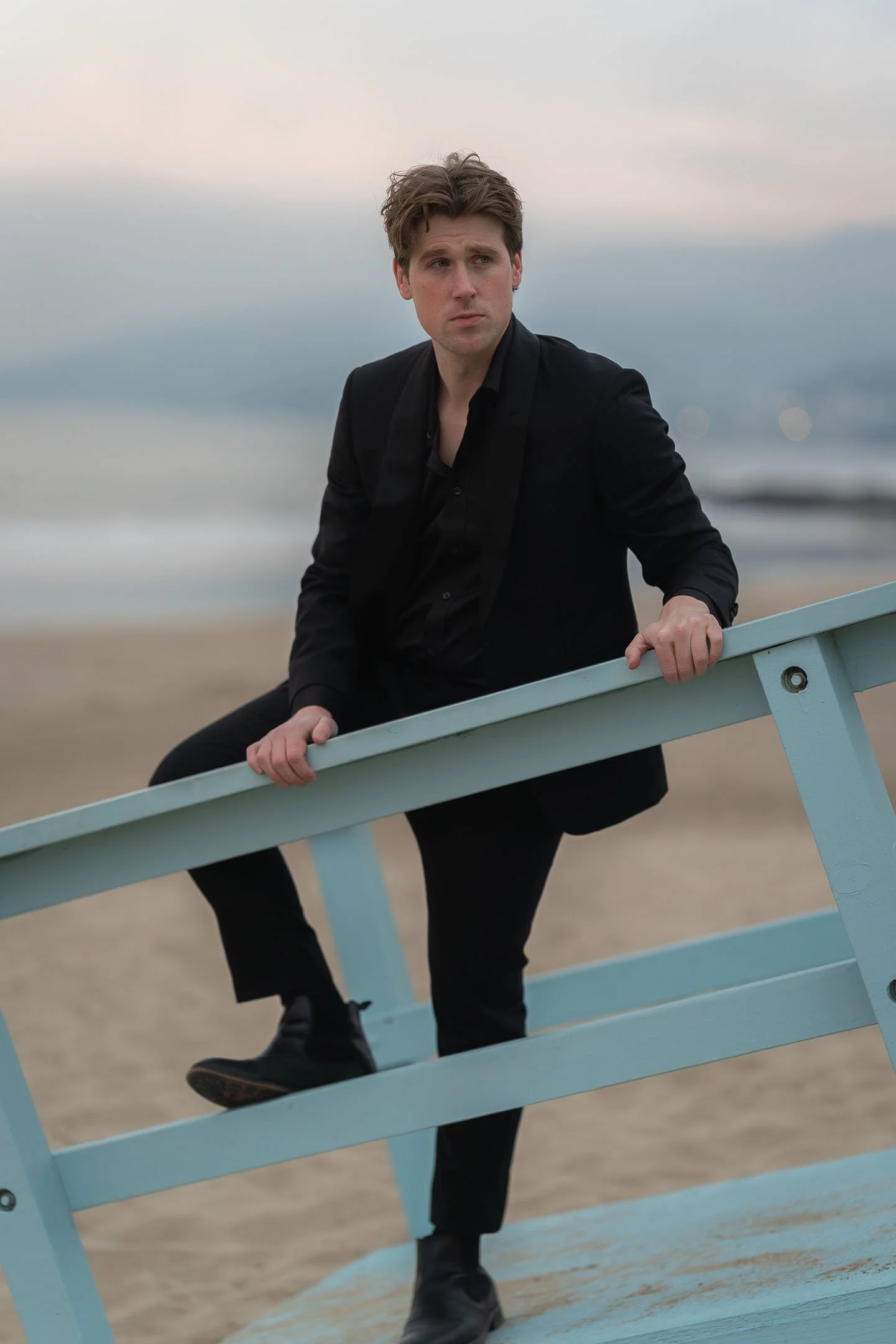 Male model wearing black suit posing on lifeguard tower