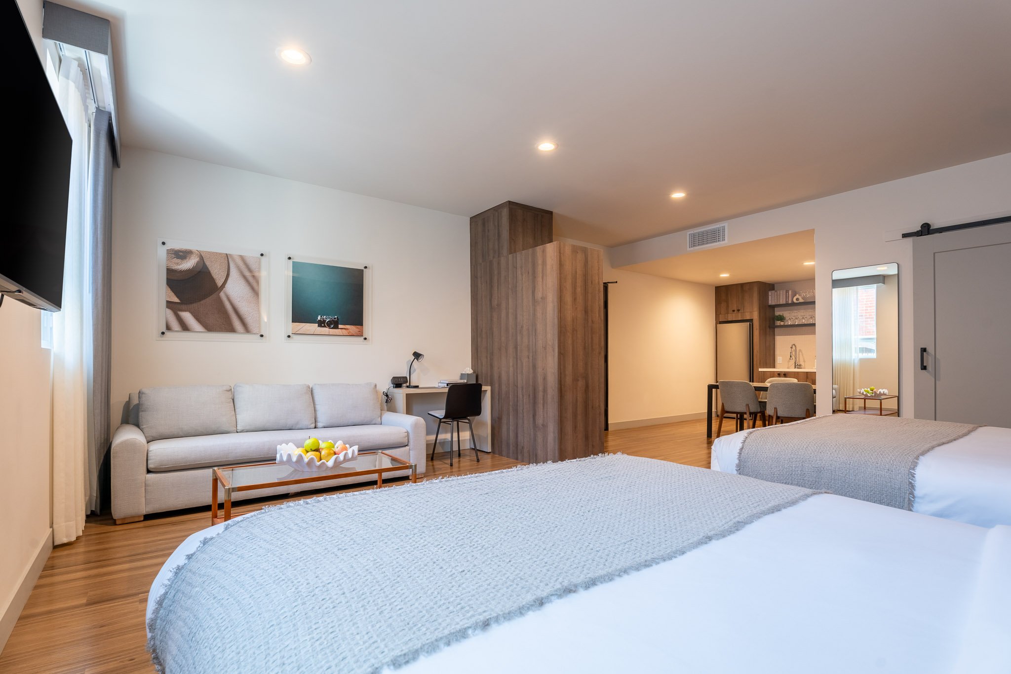 Large beds with a TV, fruit bowl and kitchen in a deluxe suite hotel room