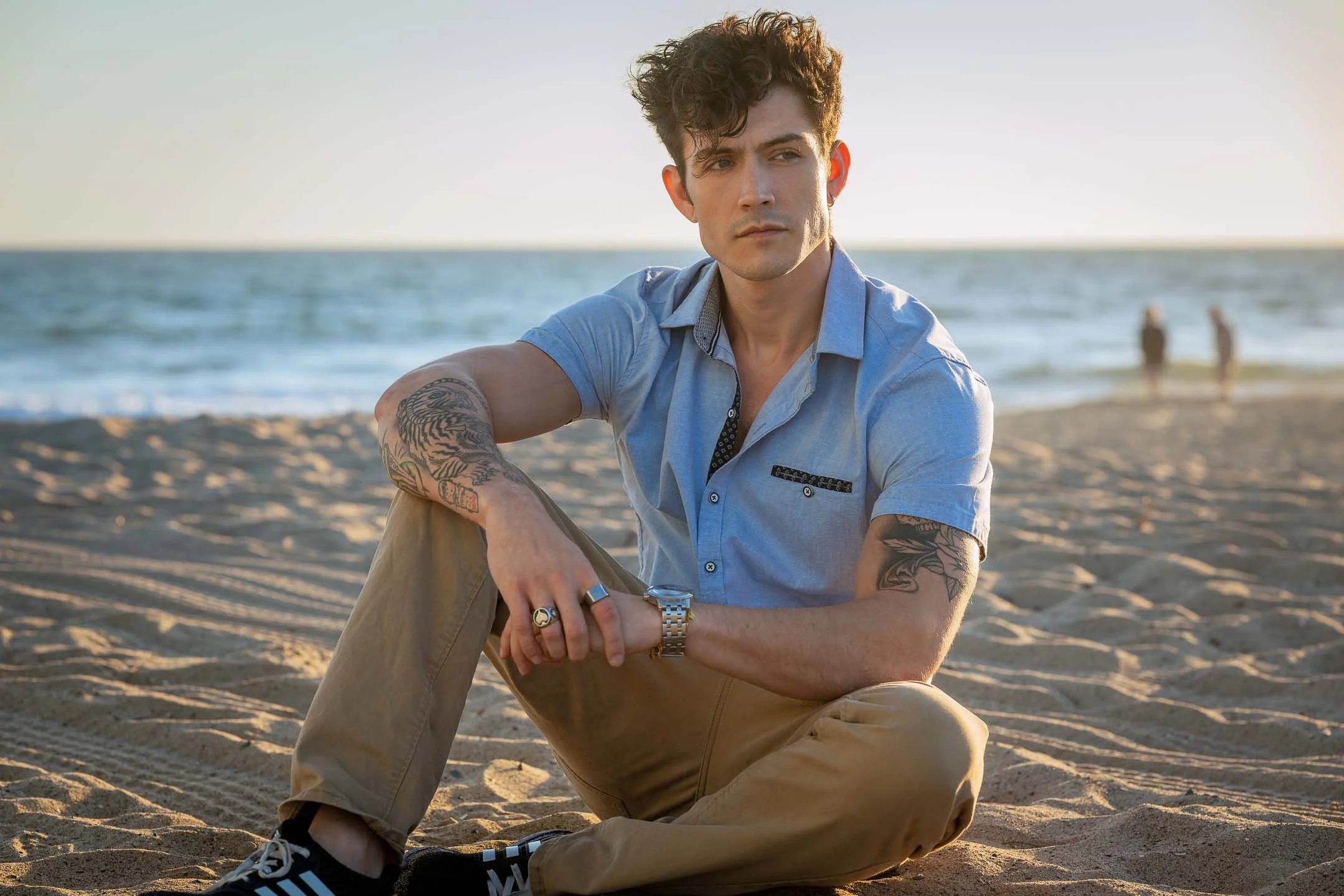 Los Angeles male model sitting on the beach at sunset at Santa Monica Beach