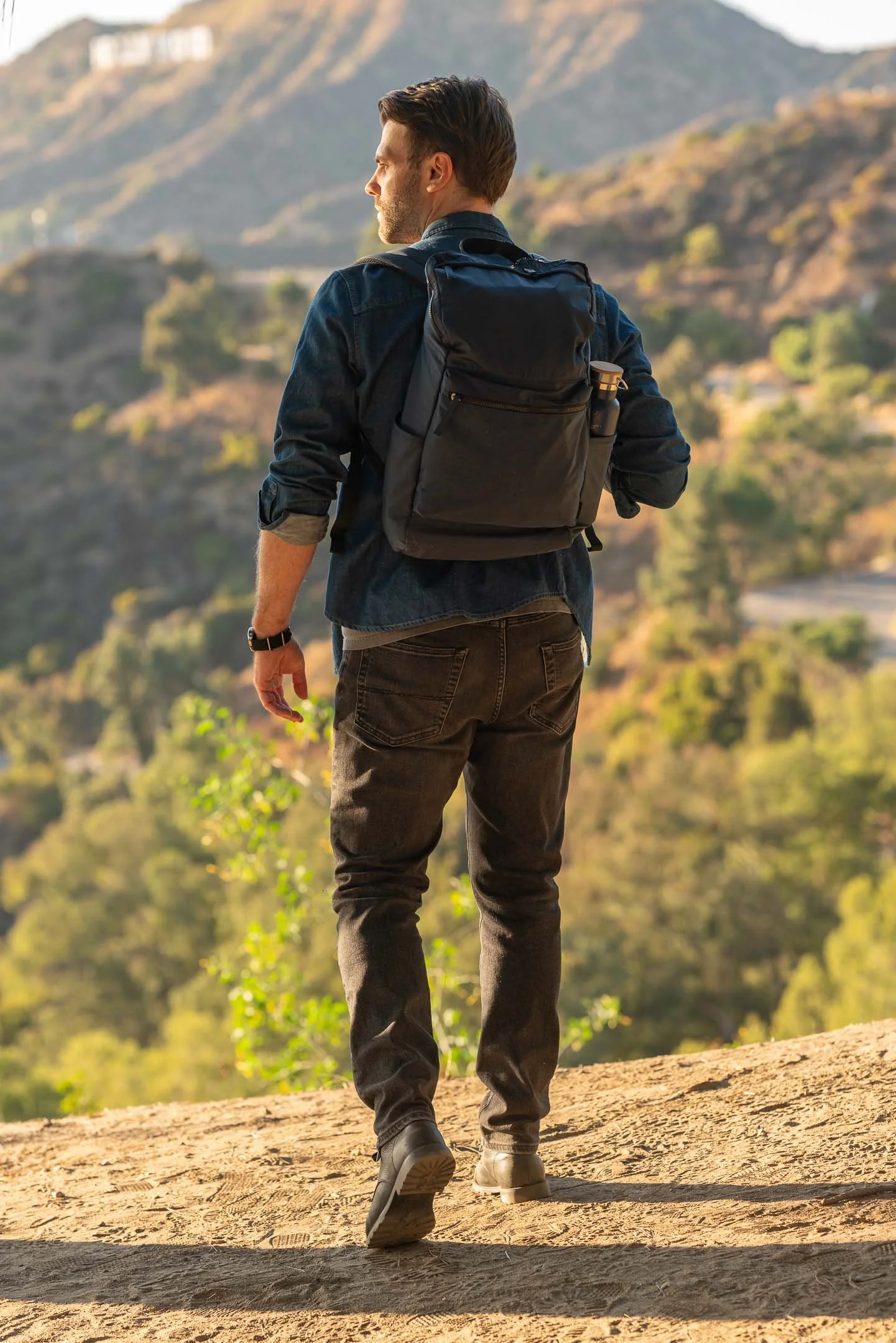 Adventurous man walking along Mount Hollywood in Griffith Park with blue backpack