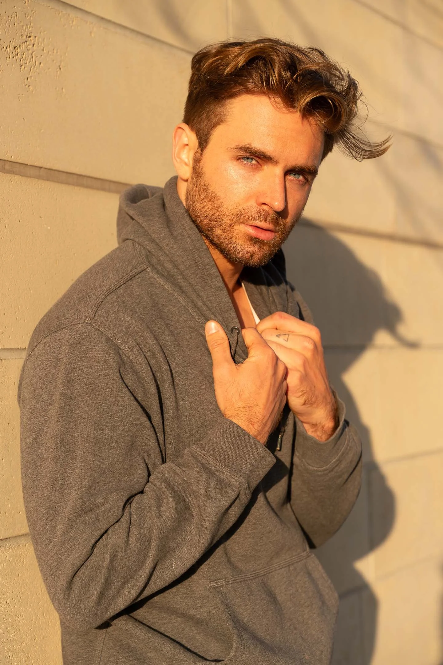 Male model posing with athleisure gray hoodie at sunset